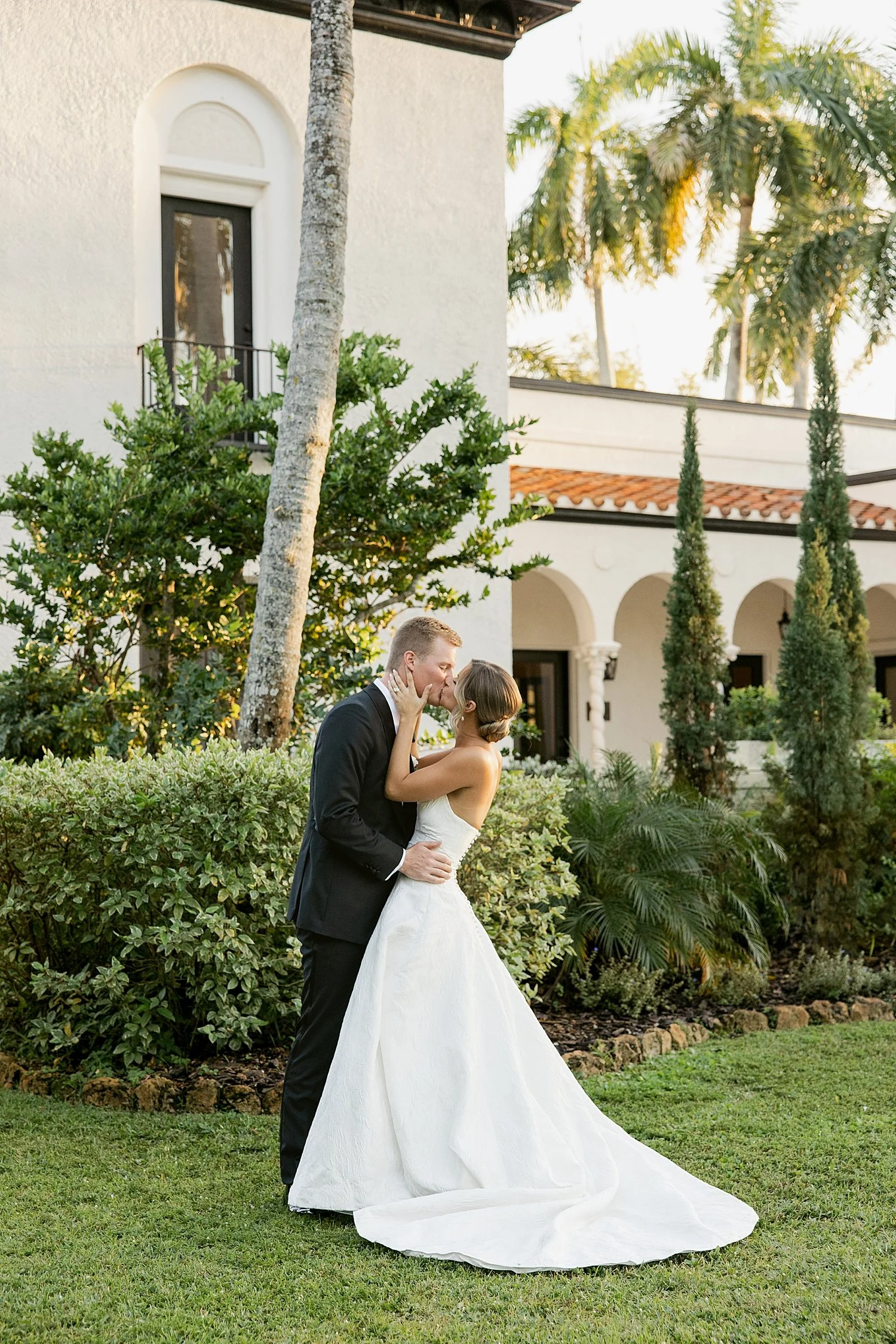  newlyweds share a kiss under palm trees by Florida wedding photographer 