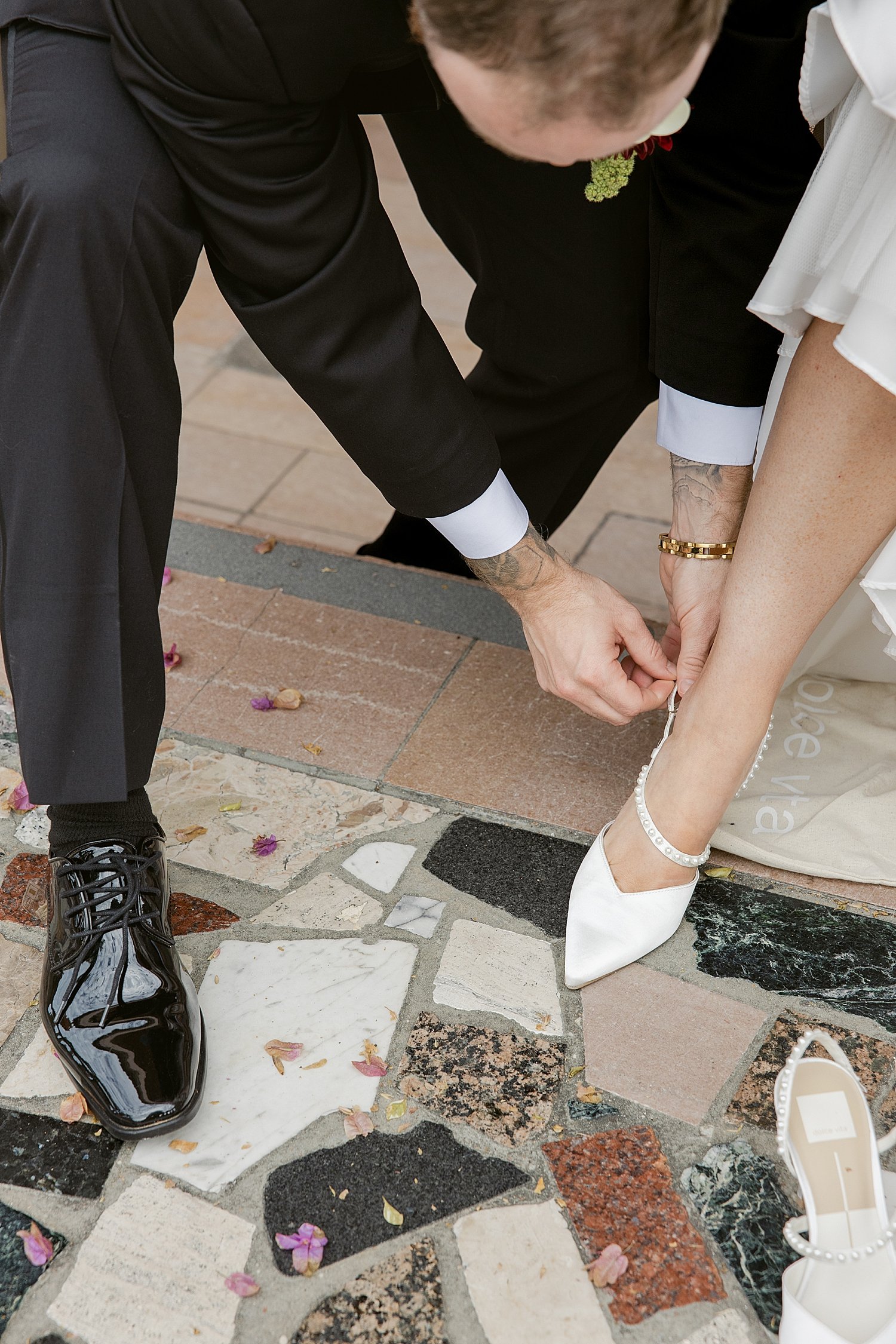  man adjusts woman’s buckle on her bridal heel for their courthouse elopement 