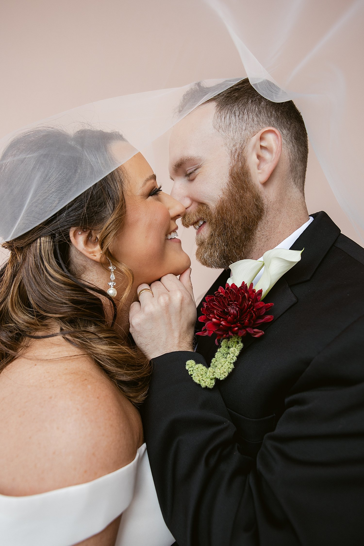  couple embraces under veil for their courthouse elopement 