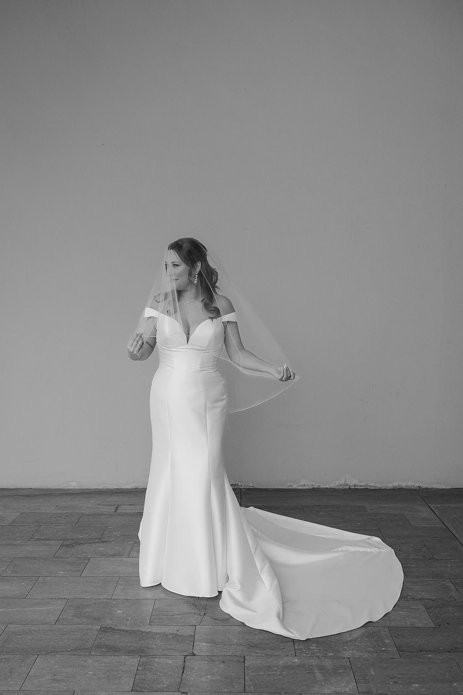  bride in an off the shoulder dress in front of a wall by Florida wedding photographer 
