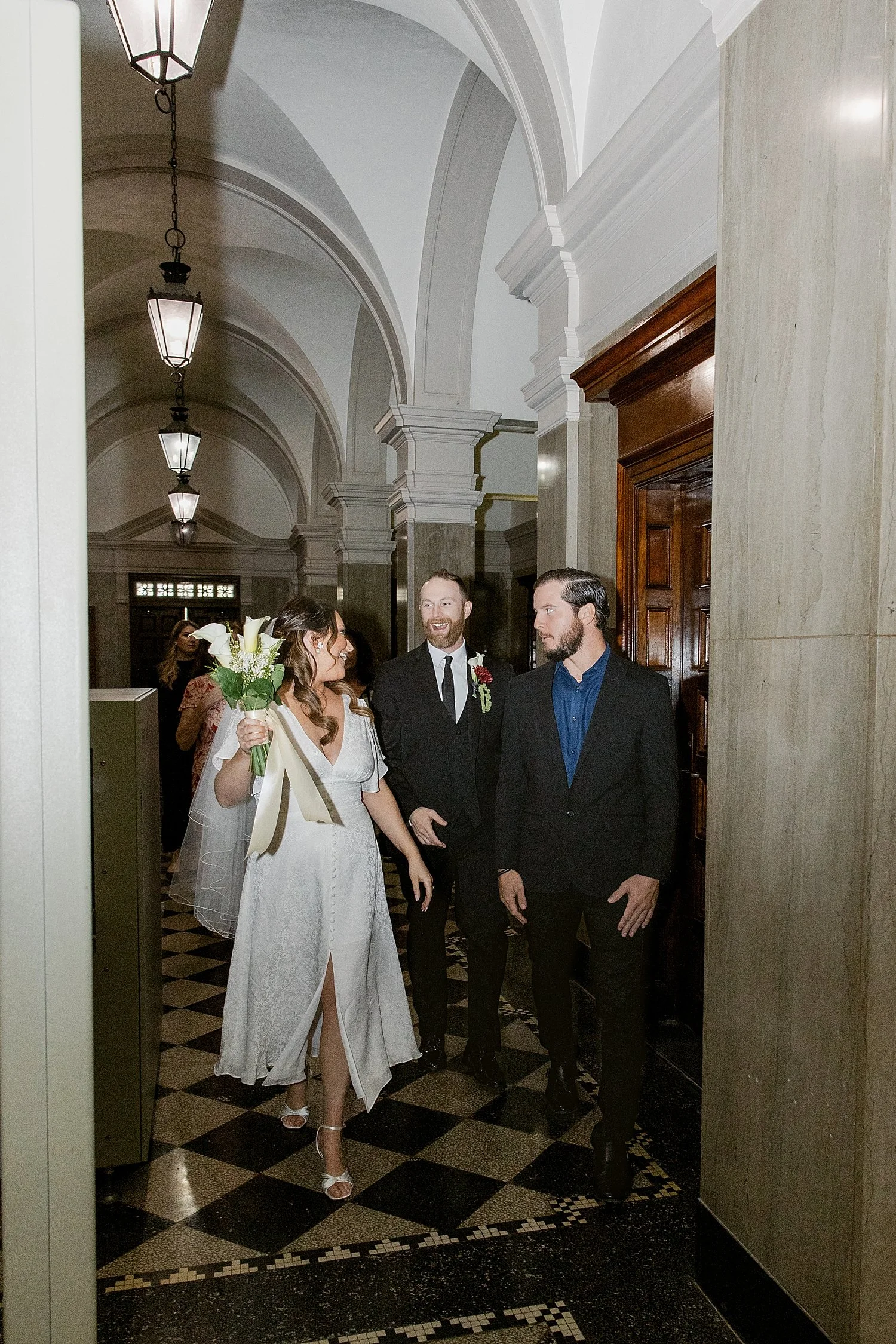  newlyweds and their close friends walk down the hallway to exit their courthouse elopement 