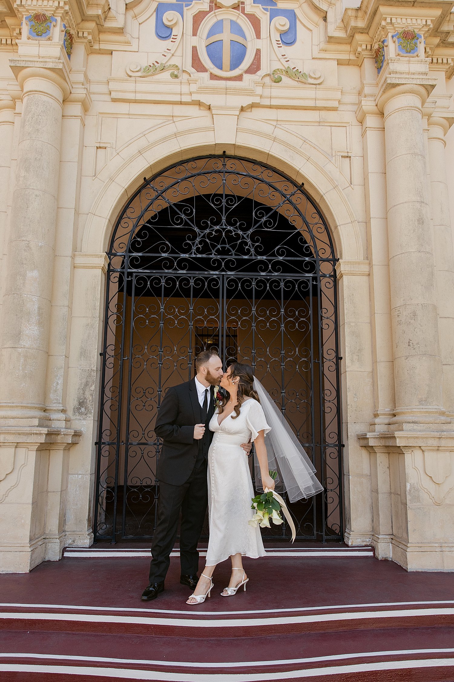  newlyweds share a kiss on official building steps by Florida wedding photographer 