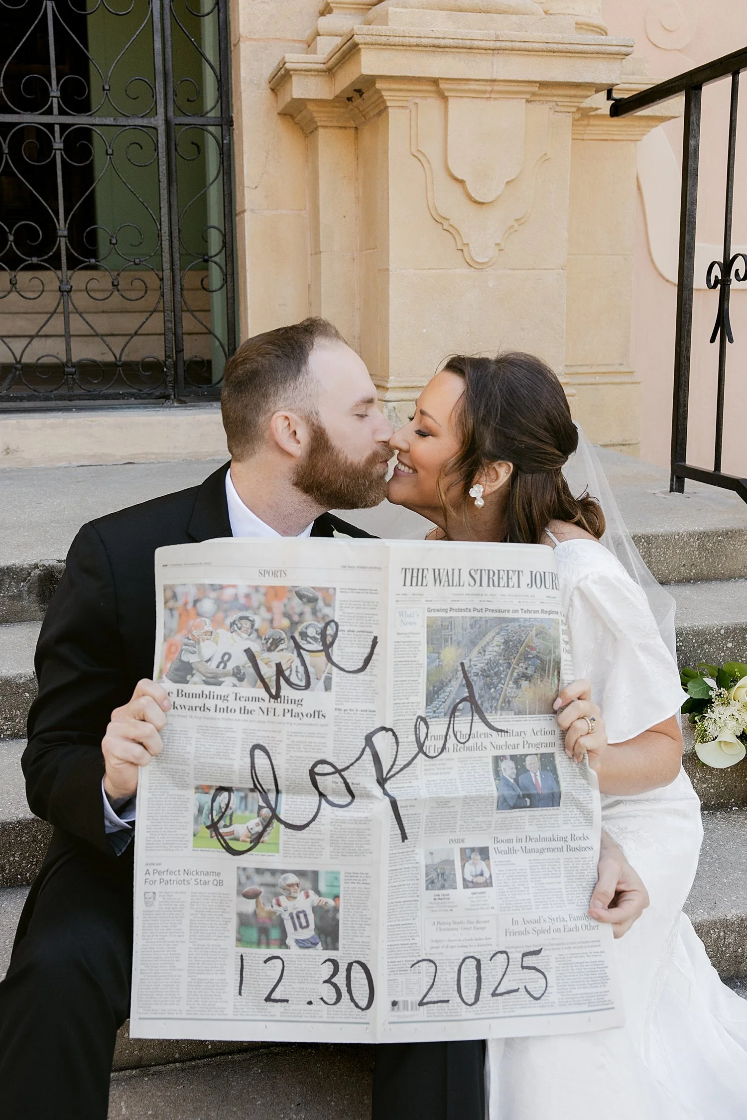  newlyweds hold up a newspaper with handwriting on it for their courthouse elopement 