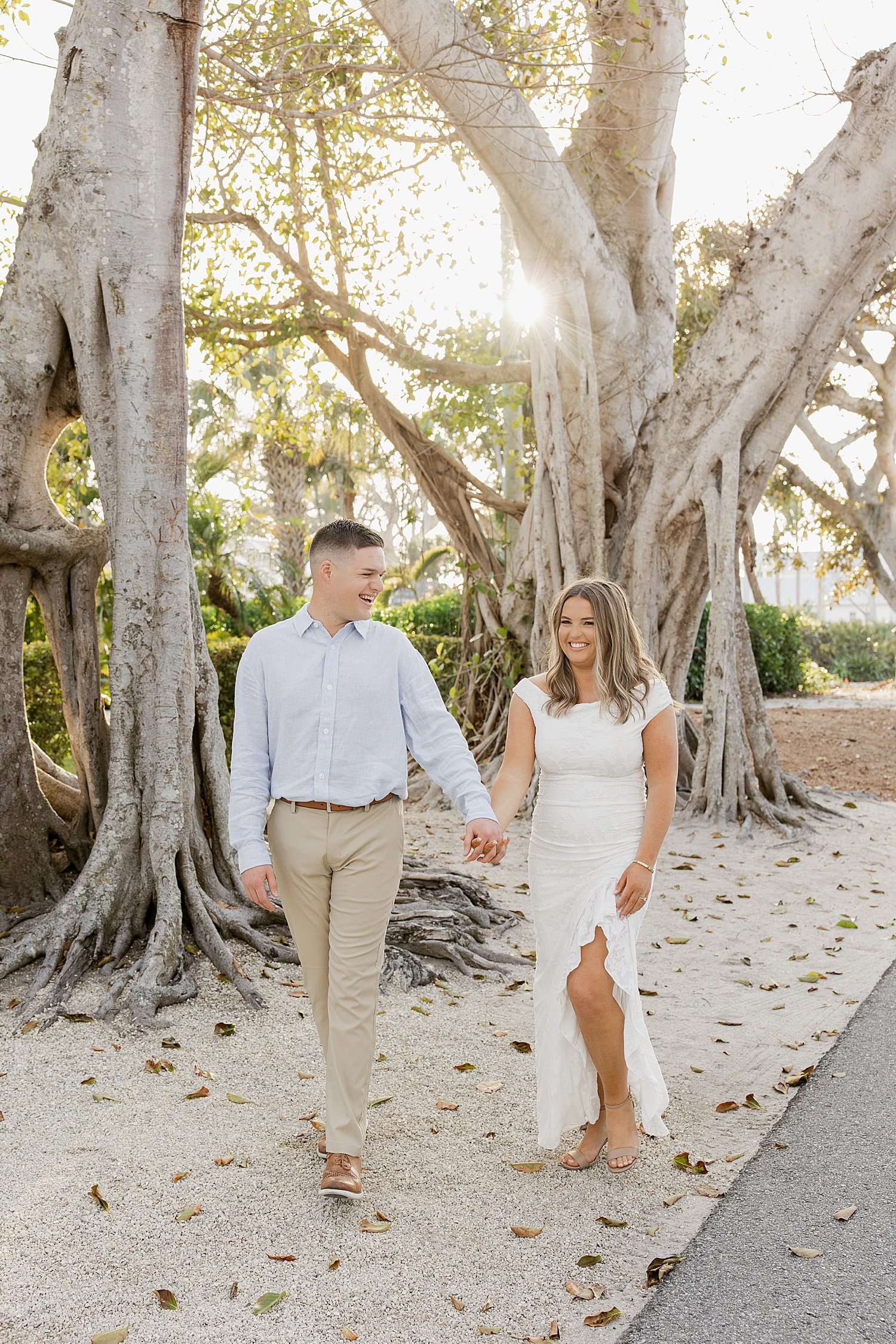  couple walk past large trees during golden hour by Taylor Shea Photo 