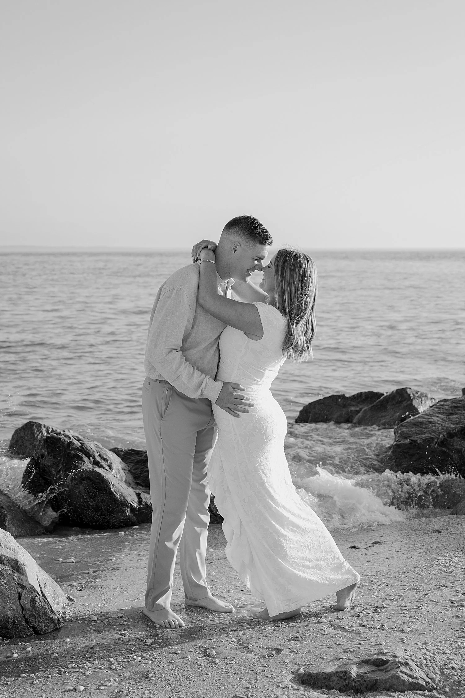  fiances embrace on the rocks near the ocean by Florida wedding photographer 