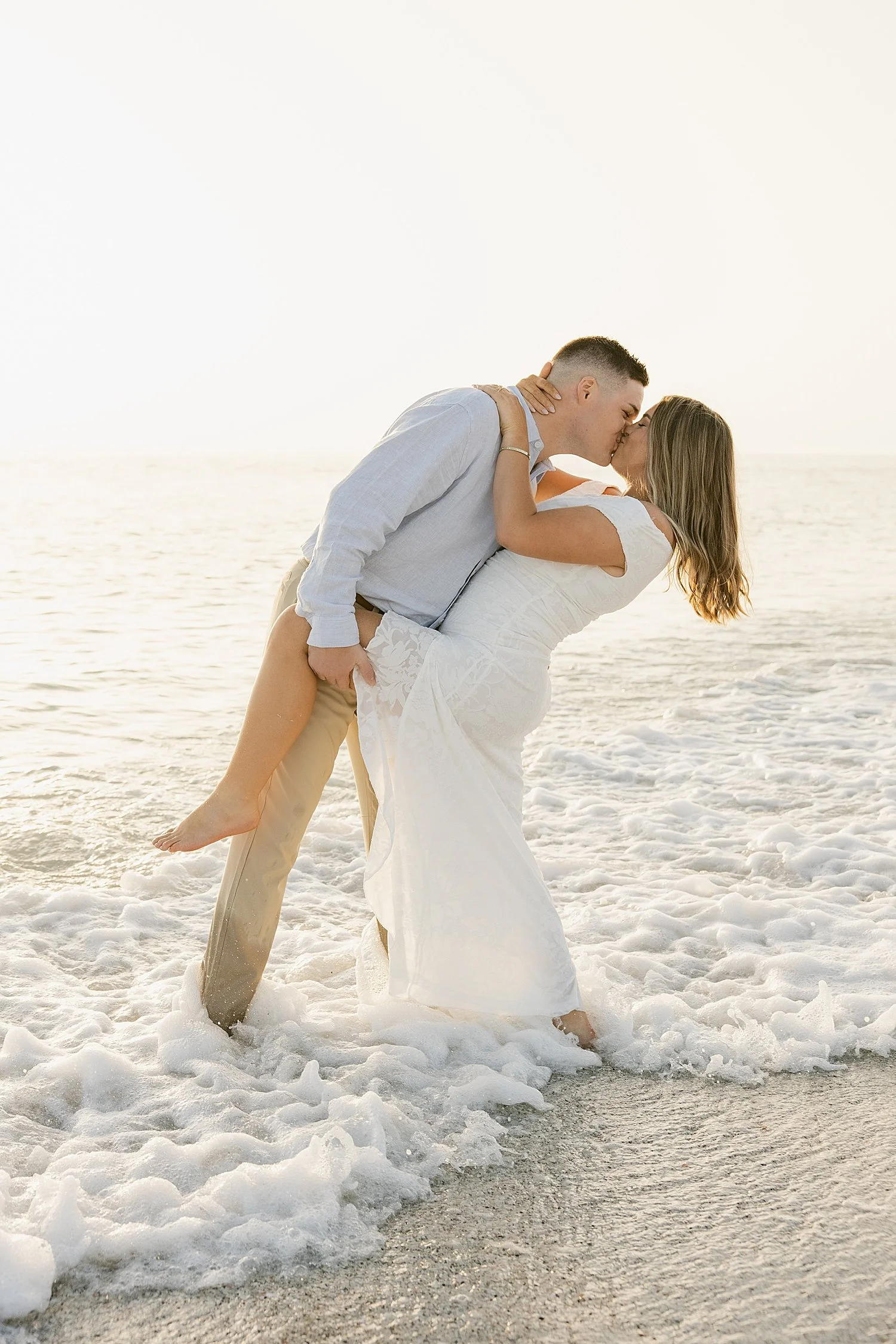  man dips fiance for a kiss standing on the shore by Florida wedding photographer 