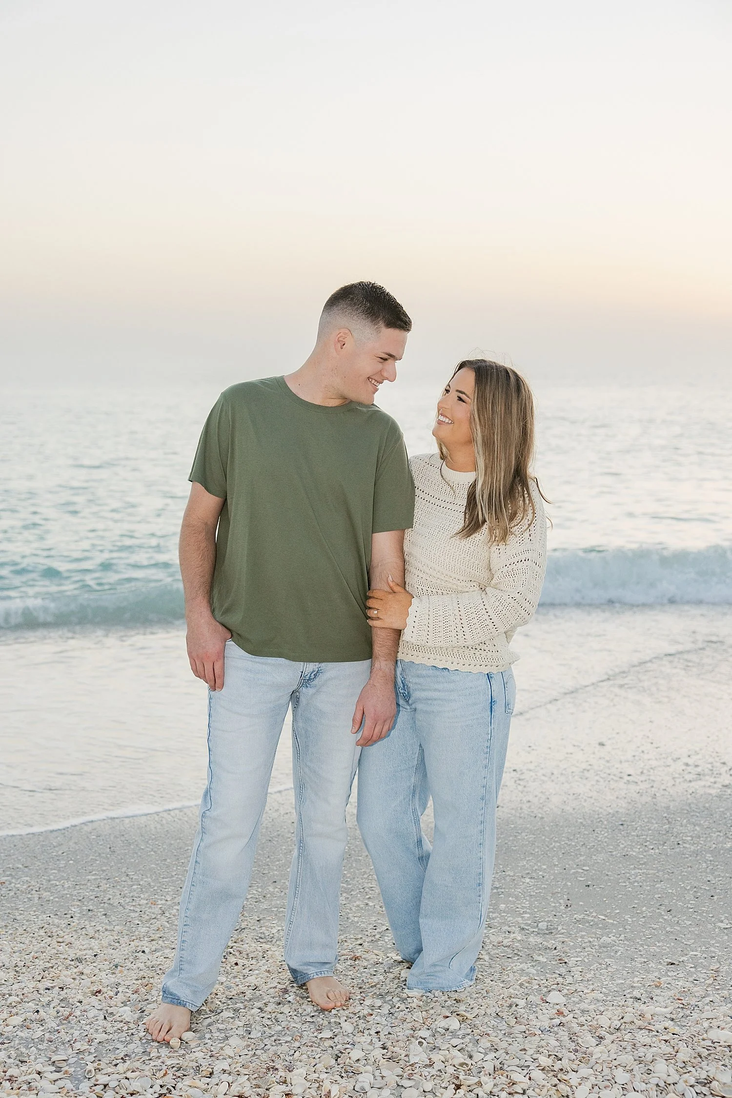  couple hold hands and look at each other standing in the sand by Florida wedding photographer 