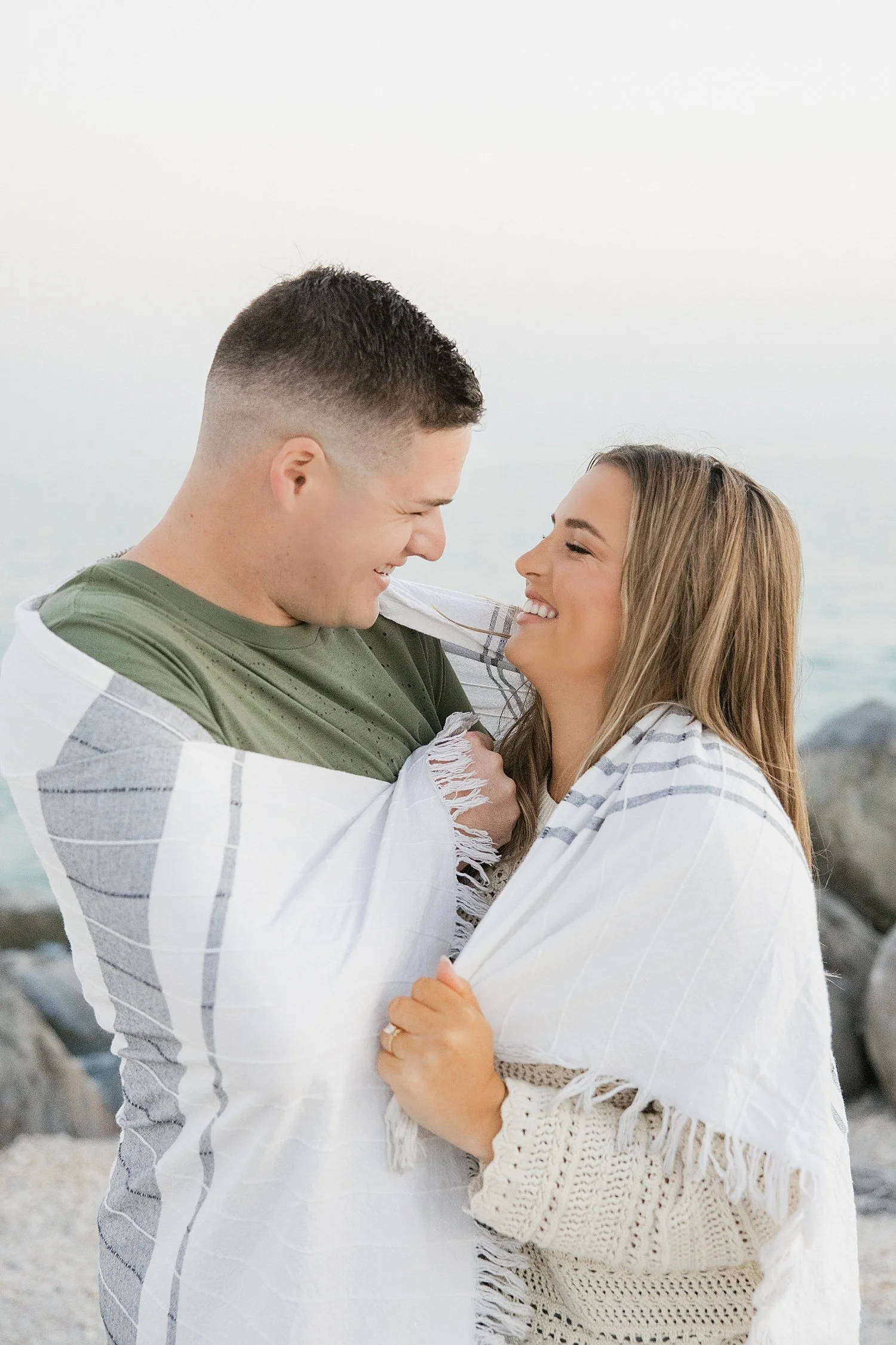  man and woman snuggle under a blanket on the beach at Boca Grande Island 