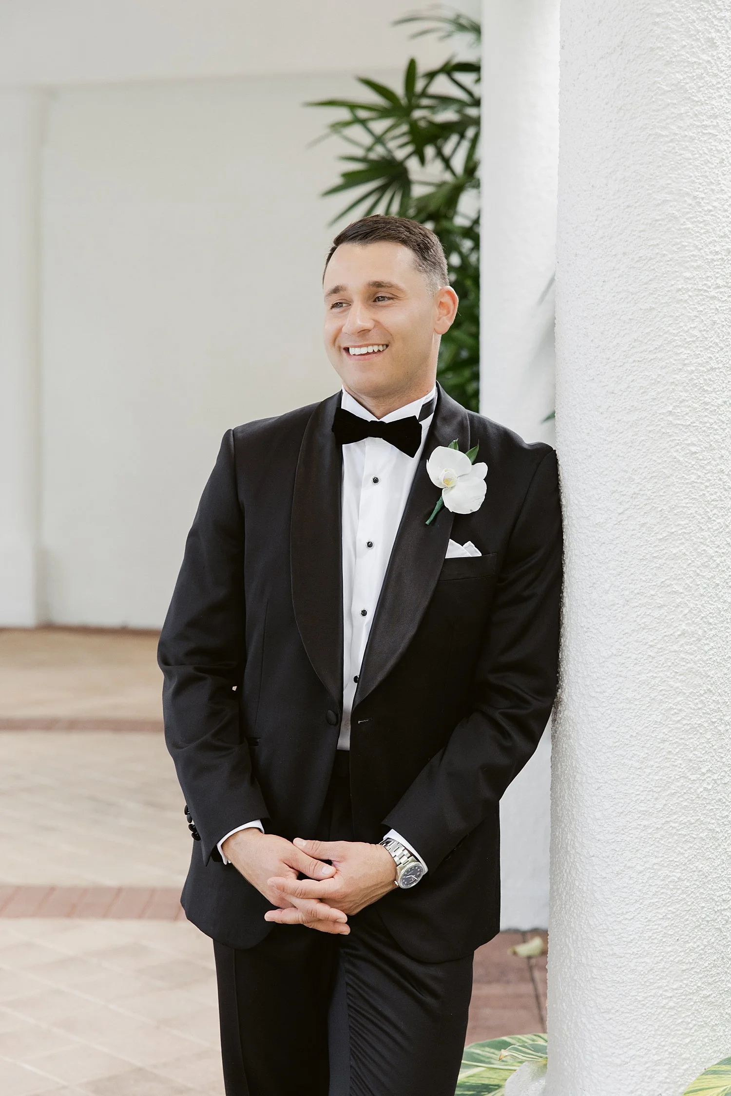  groom in black suit leans against column by Taylor Shea Photo 