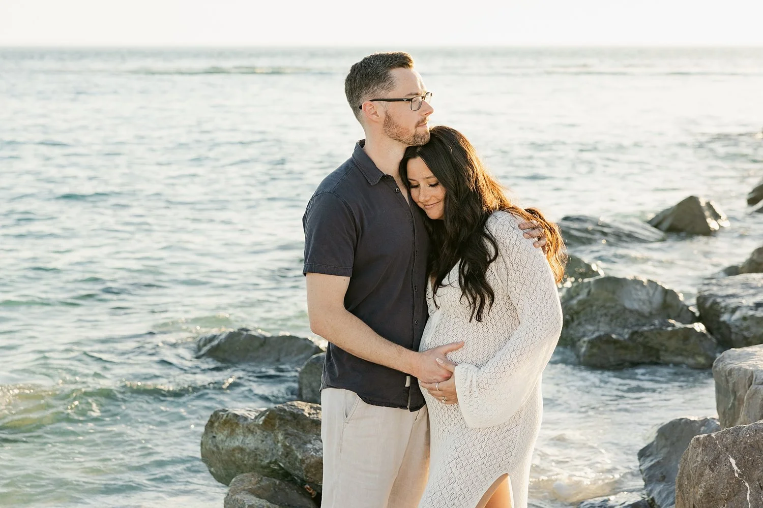  couple snuggle together cradling her pregnant belly next to water by Florida wedding photographer 