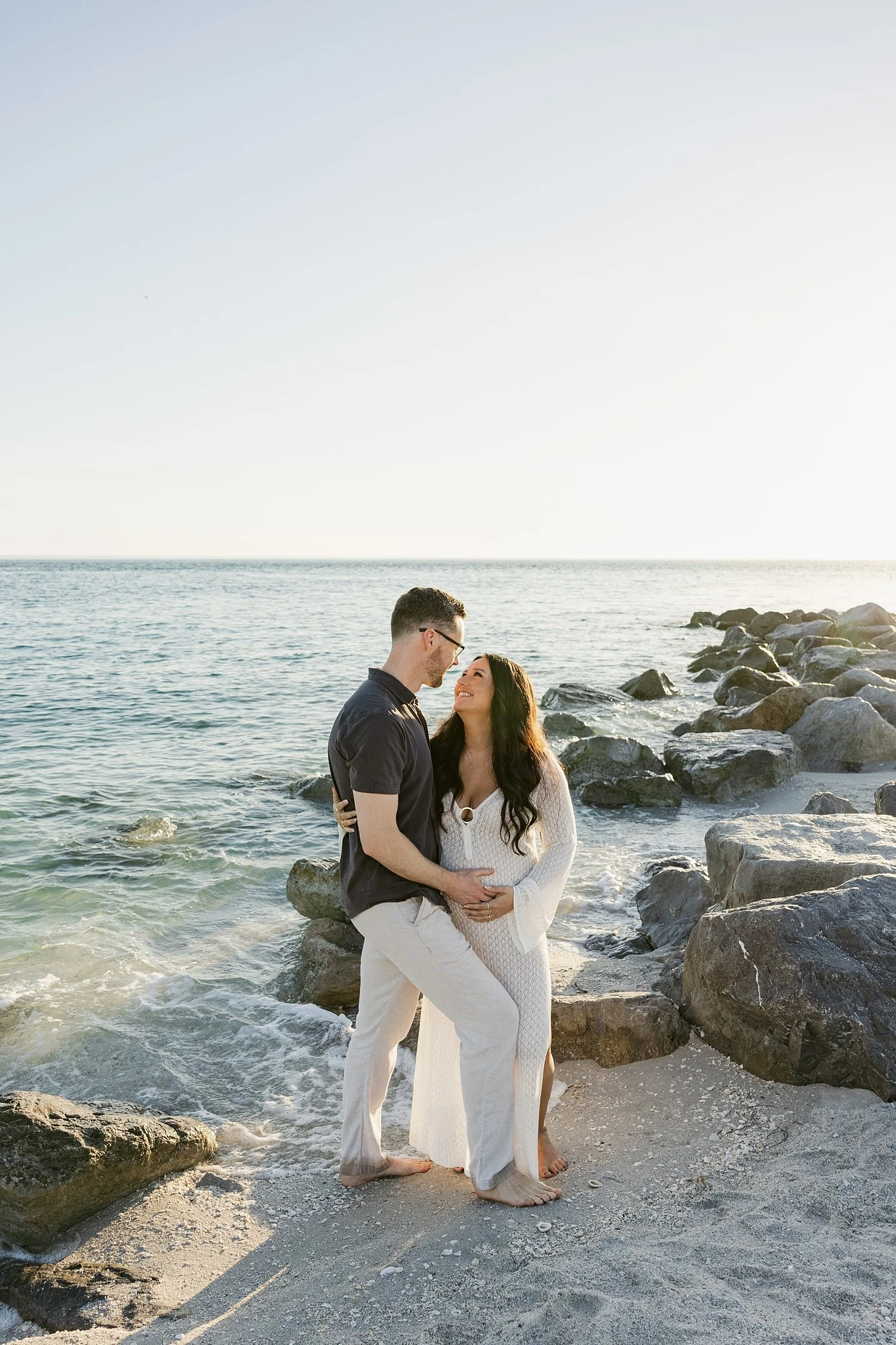  couple stands on ocean in sunset lighting by Florida wedding photographer 