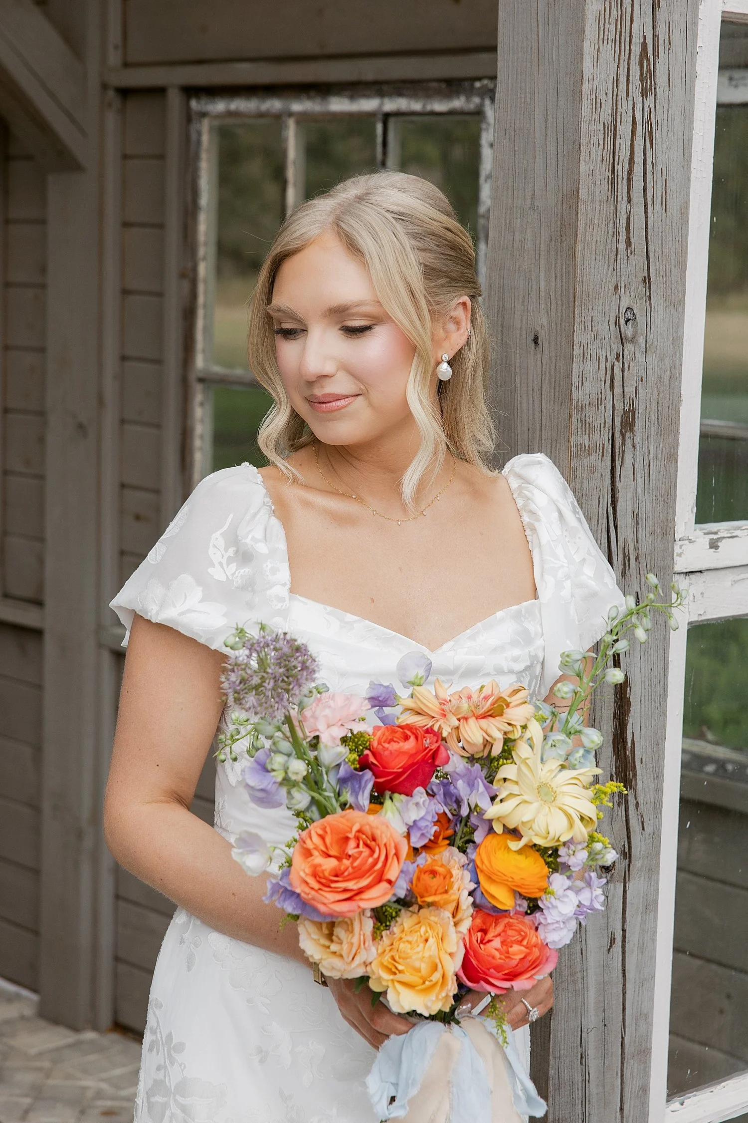  bride with colorful flowers stands outside at Mill Pond Estate 