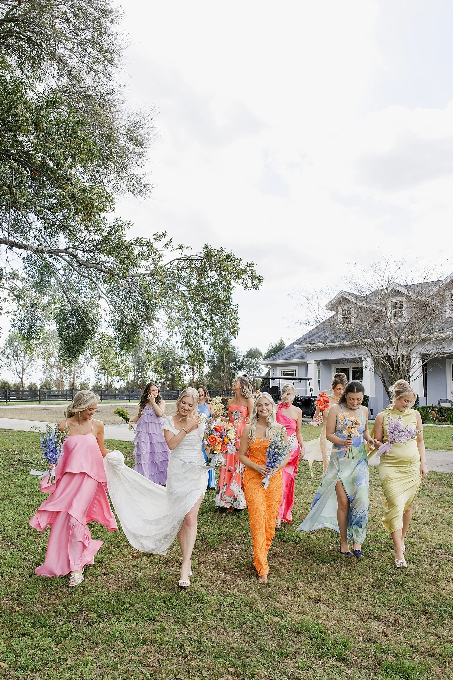  wedding party in bright, colorful dresses on field at Mill Pond Estate 