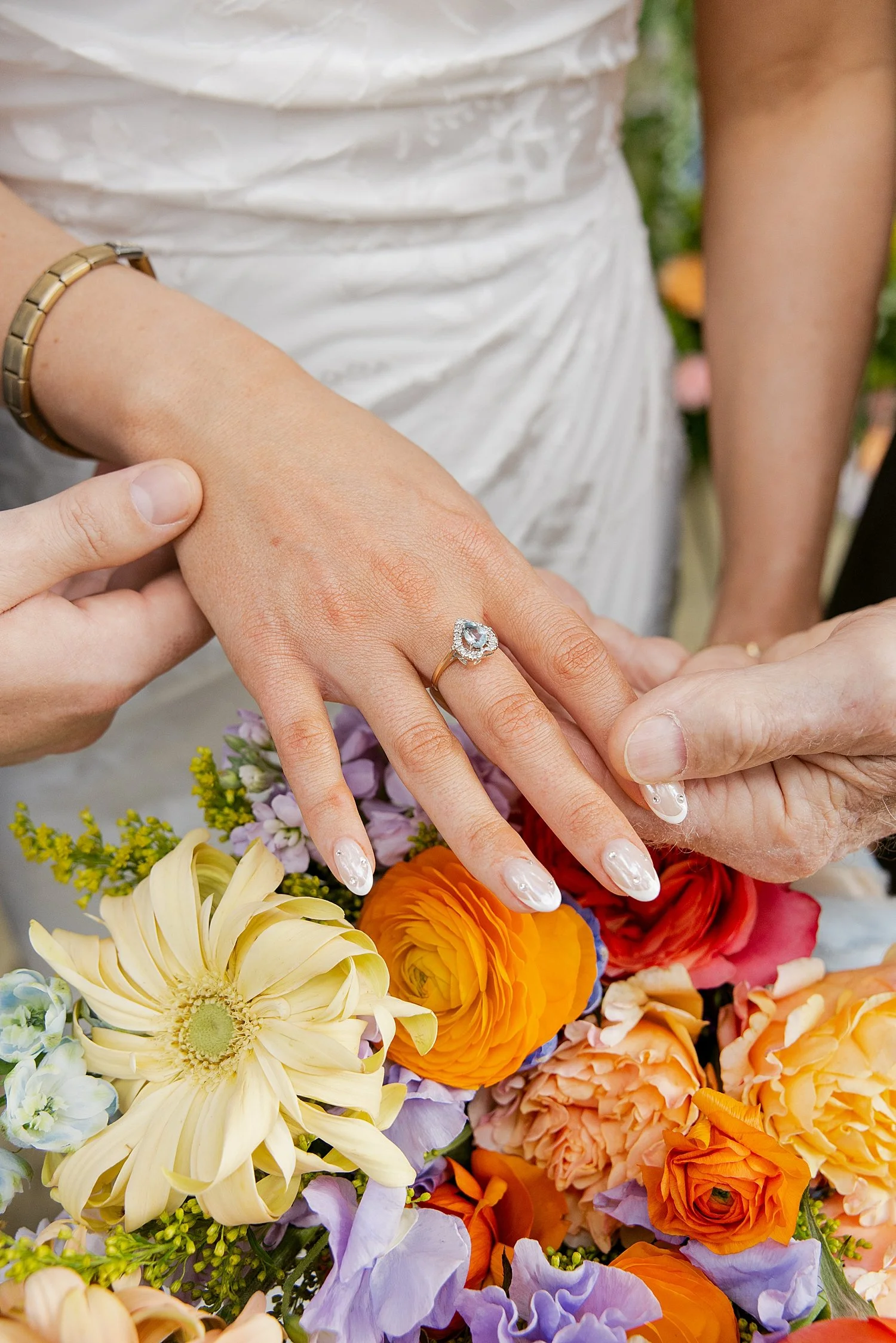  bride shows off her diamond ring on top of orange and yellow flowers by Taylor Shea Photo 