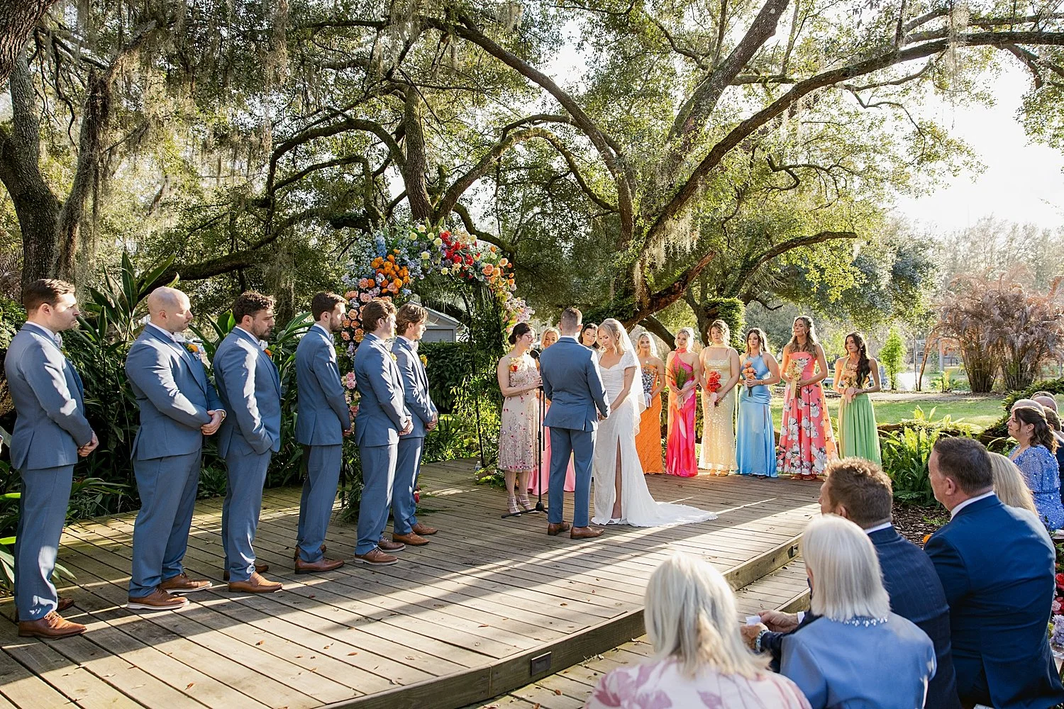  groomsmen in navy and bridesmaids in colors stand next to alter by Florida wedding photographer 