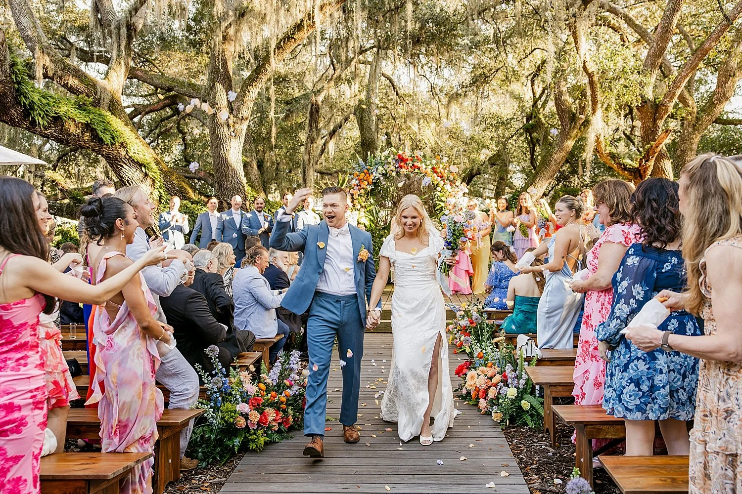  newlyweds raise their hands in celebration walking down the aisle by Florida wedding photographer 