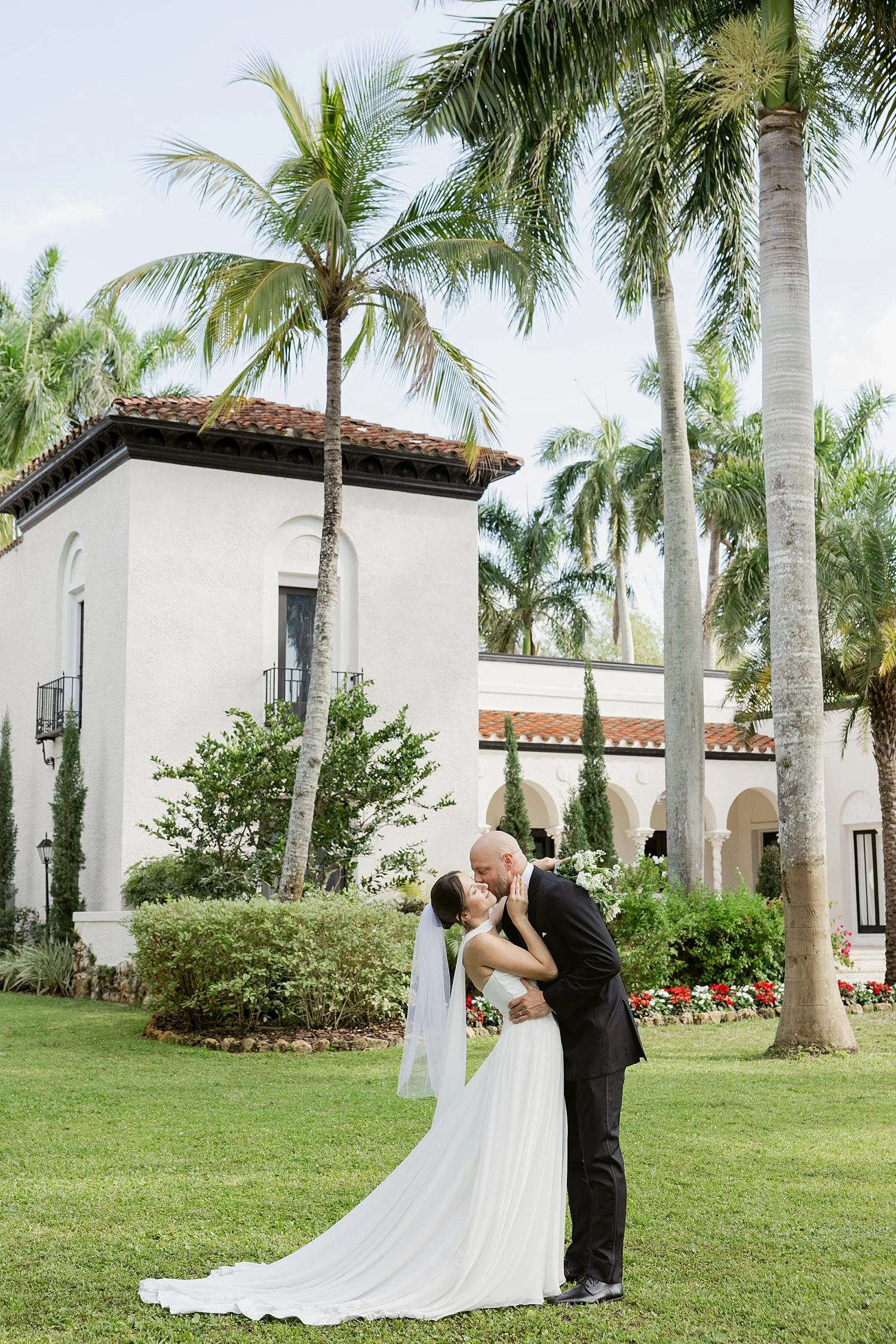  couple share a kiss under big palm tree after ceremony by Taylor Shea Photo 