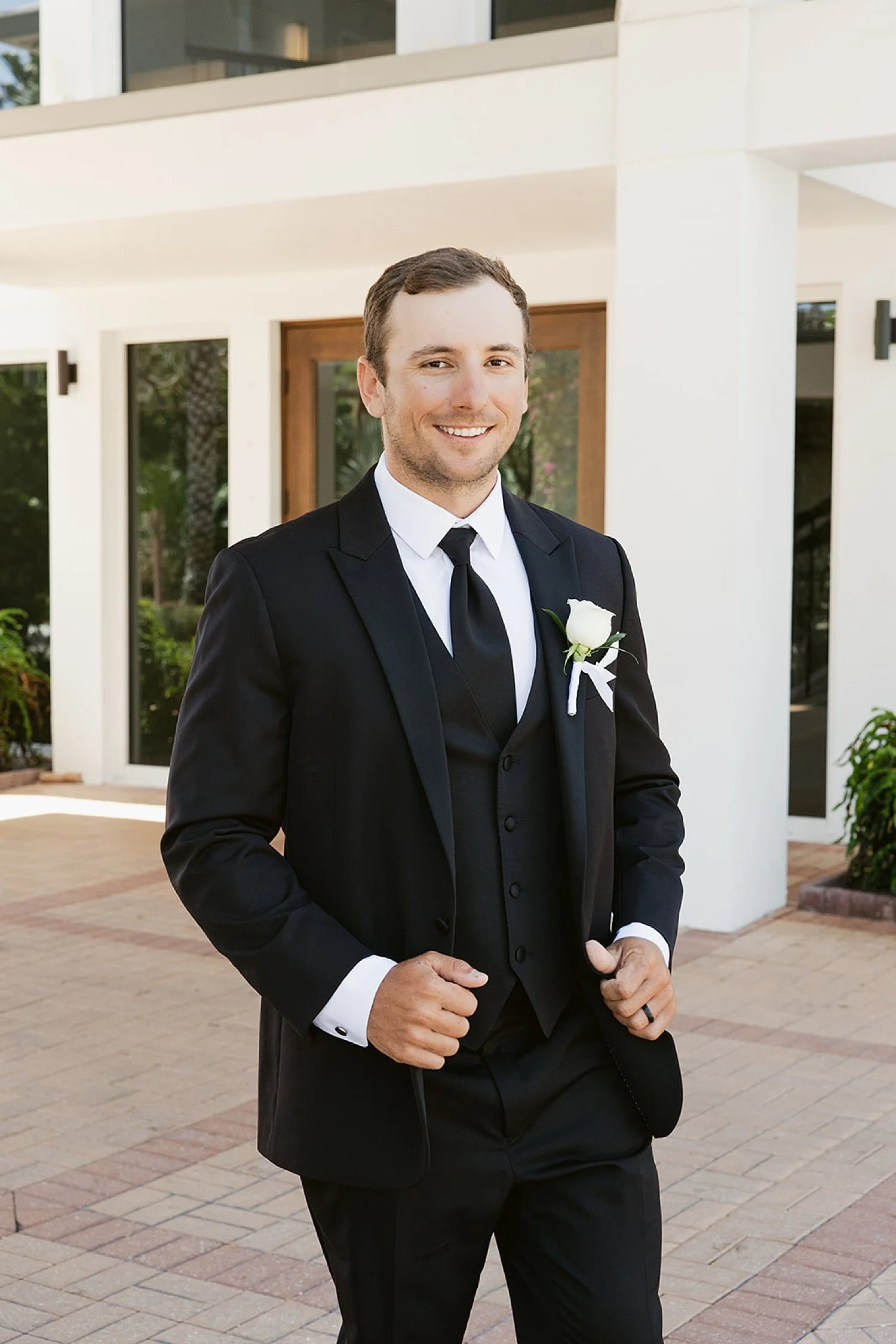  man in black suit and tie in front of venue by Taylor Shea Photo 