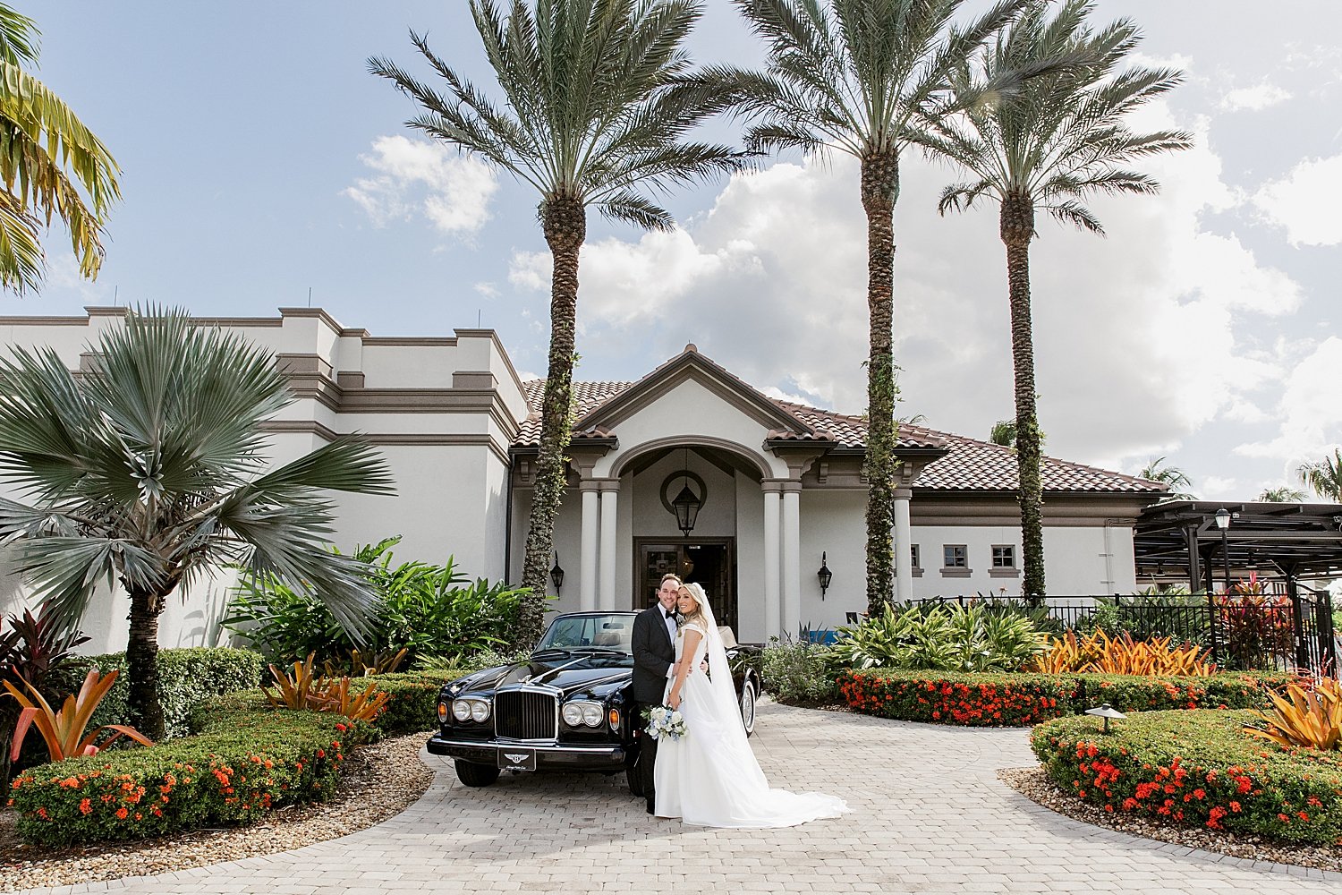  newlyweds stand outside of Bentley under palm trees by Florida photographer 