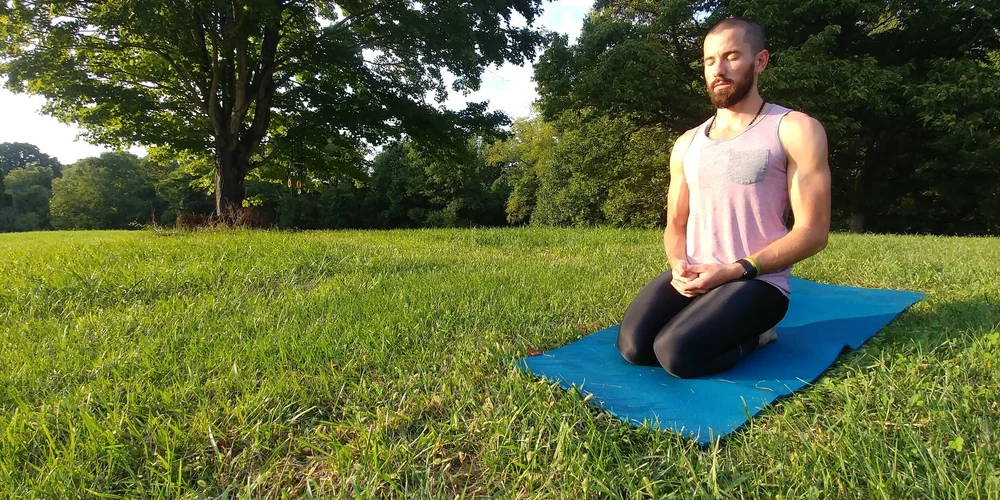 Aaron Wayne Richards seated on a yoga mat outdoors