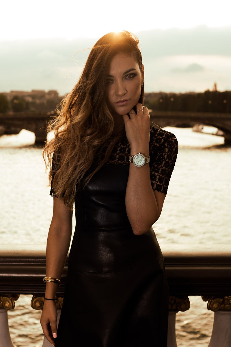 Ce portrait rapproché de Hanna Patapovitch, pris sur le pont Alexandre III à Paris, met en lumière son expression à la fois confiante et mystérieuse. Portant la même robe noire en cuir, associée à des détails en dentelle, elle incarne une sophistica