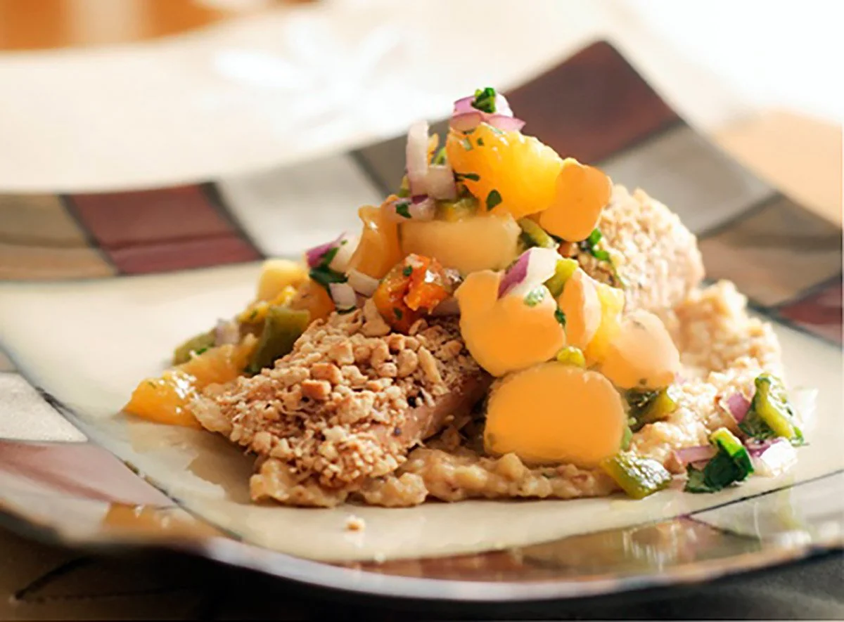 A plate of mashed potatoes with vegetable topping and gravy, garnished with chopped onions and herbs.