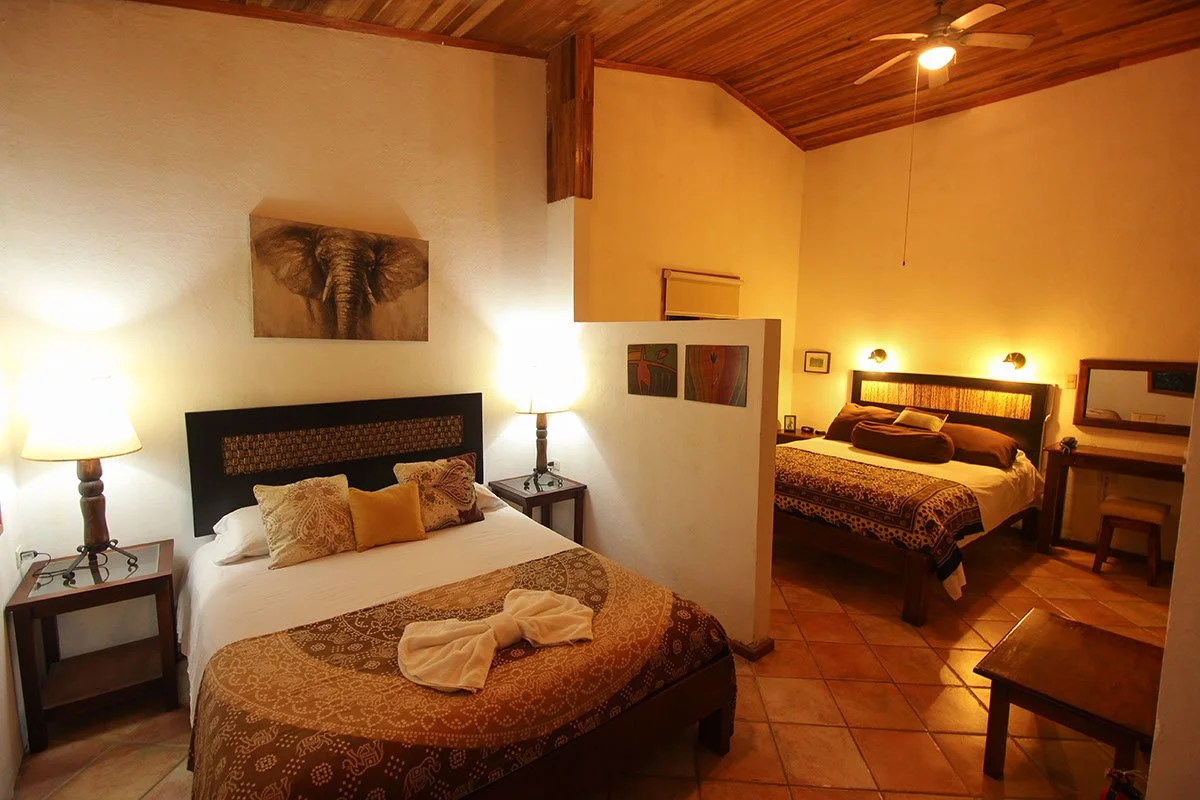 Two bedrooms with wooden accents, lamps, paintings, and a ceiling fan, decorated in warm earthy tones.