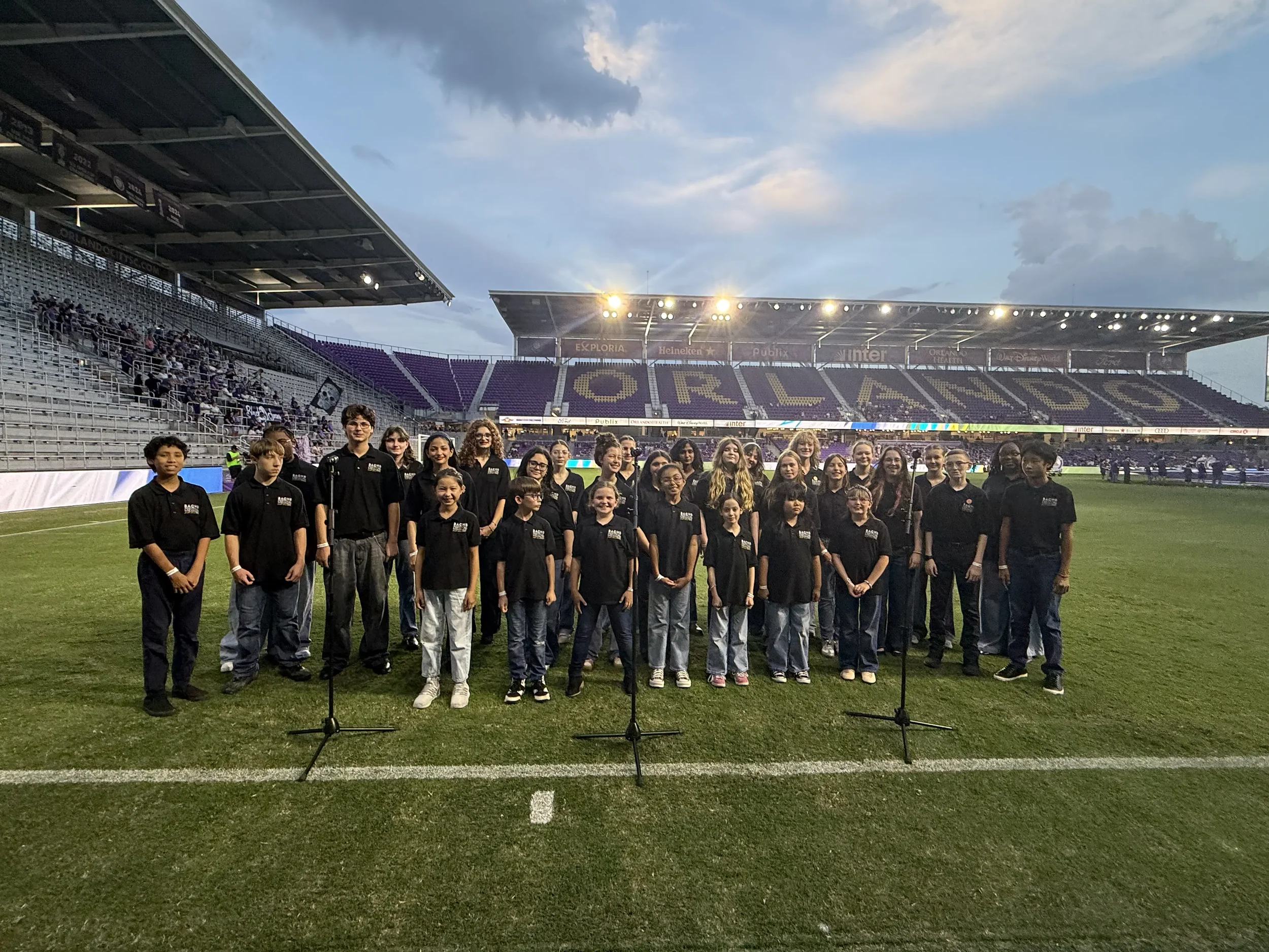 Image shows the Bach Festival Youth Choir preparing to sing the National Anthem at the Orlando Pride Soccer game. The Bach Festival Youth Choir is a group composed of approximately 30 singers between grades 6-12.
