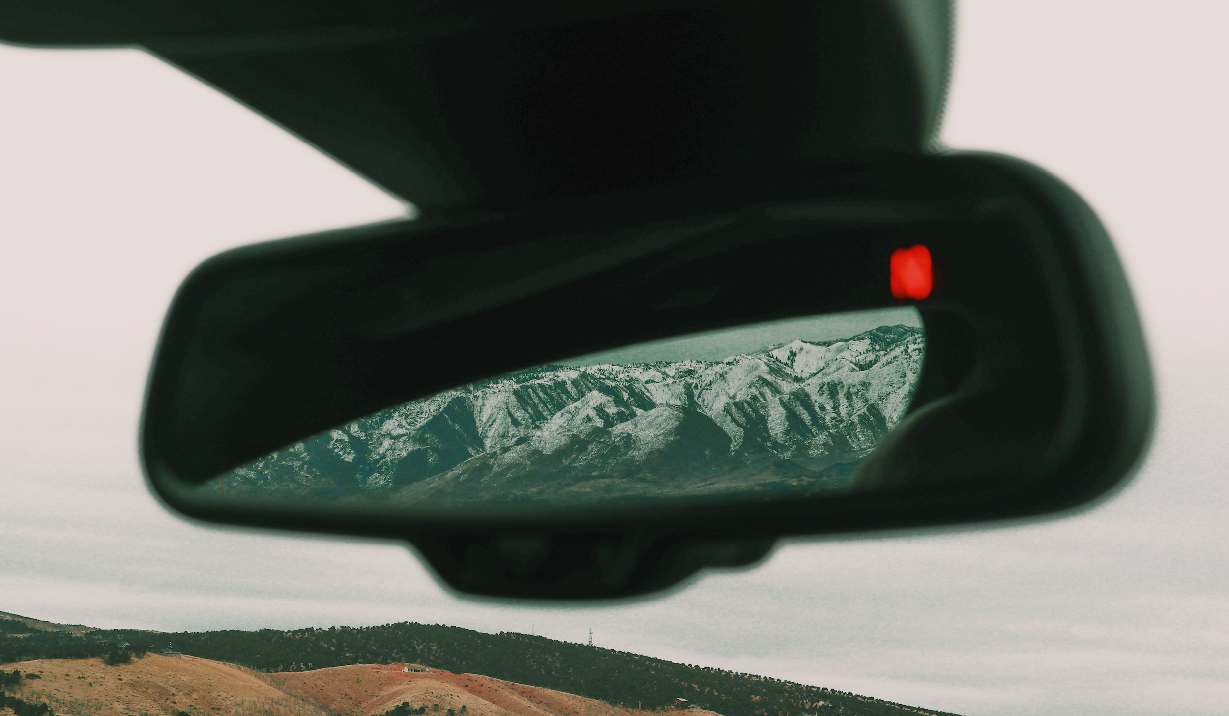 Image of rear-view mirror with mountains and snow.