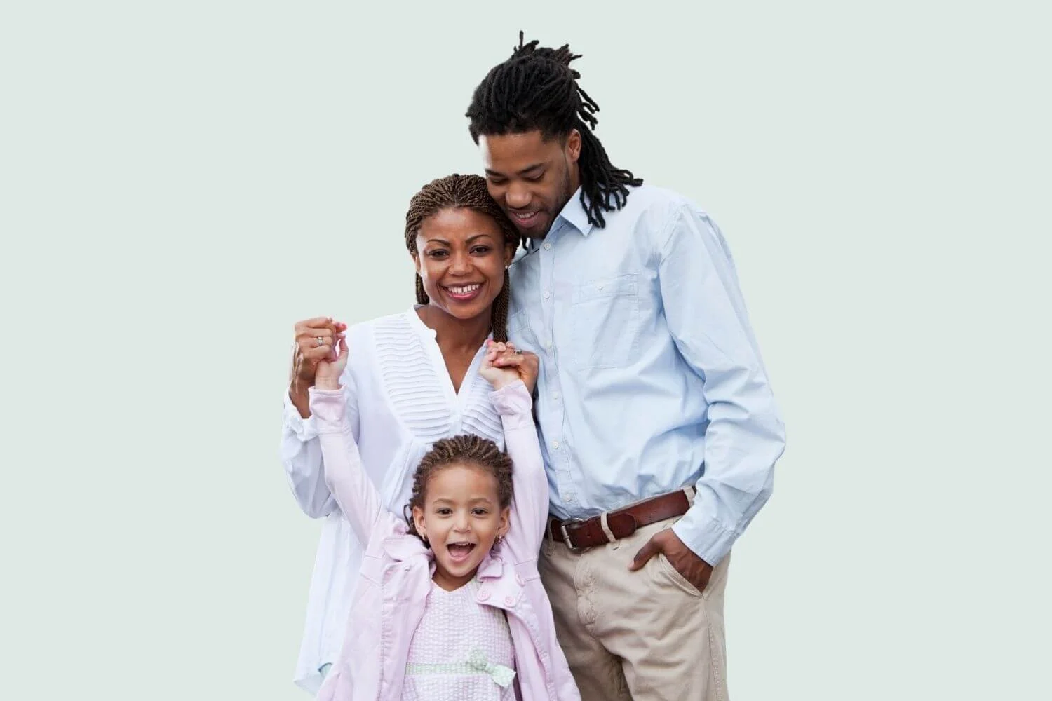 Parents standing with their young daughter, holding her hands as she smiles.