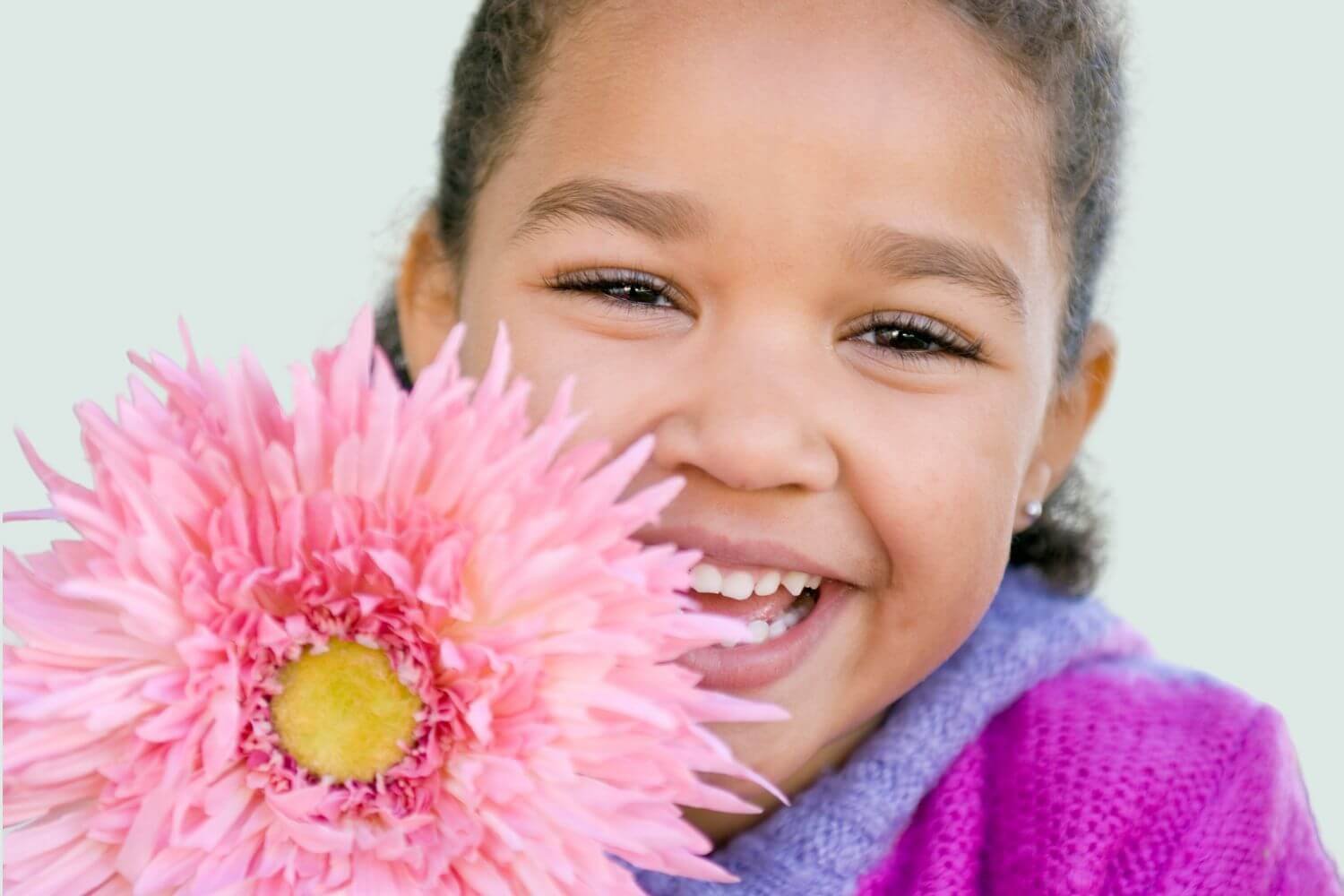 close-up of a girl smiling with large pink flower