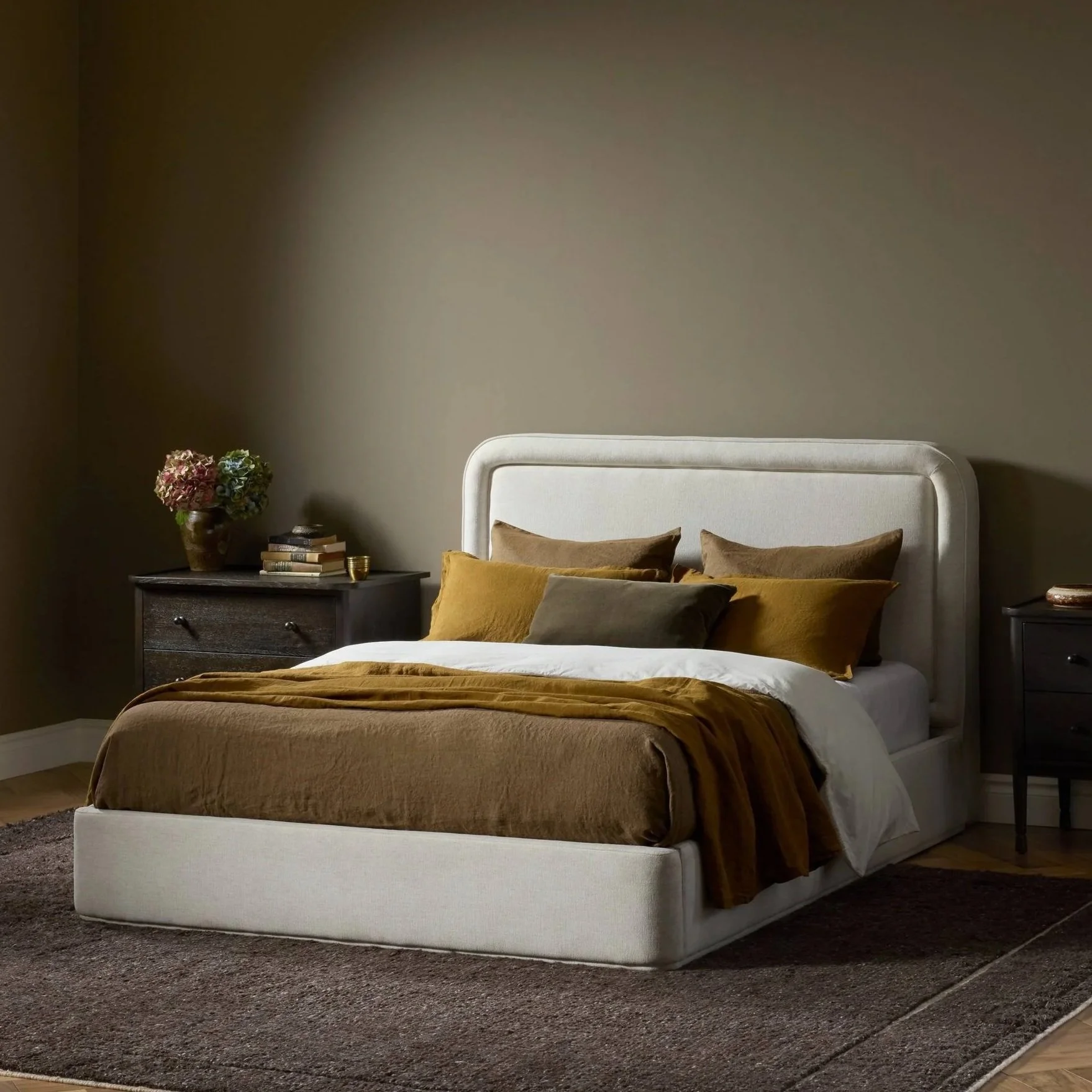 Warm minimalist bedroom with textured plaster walls, wood beam ceiling, upholstered bed, and soft ambient lighting