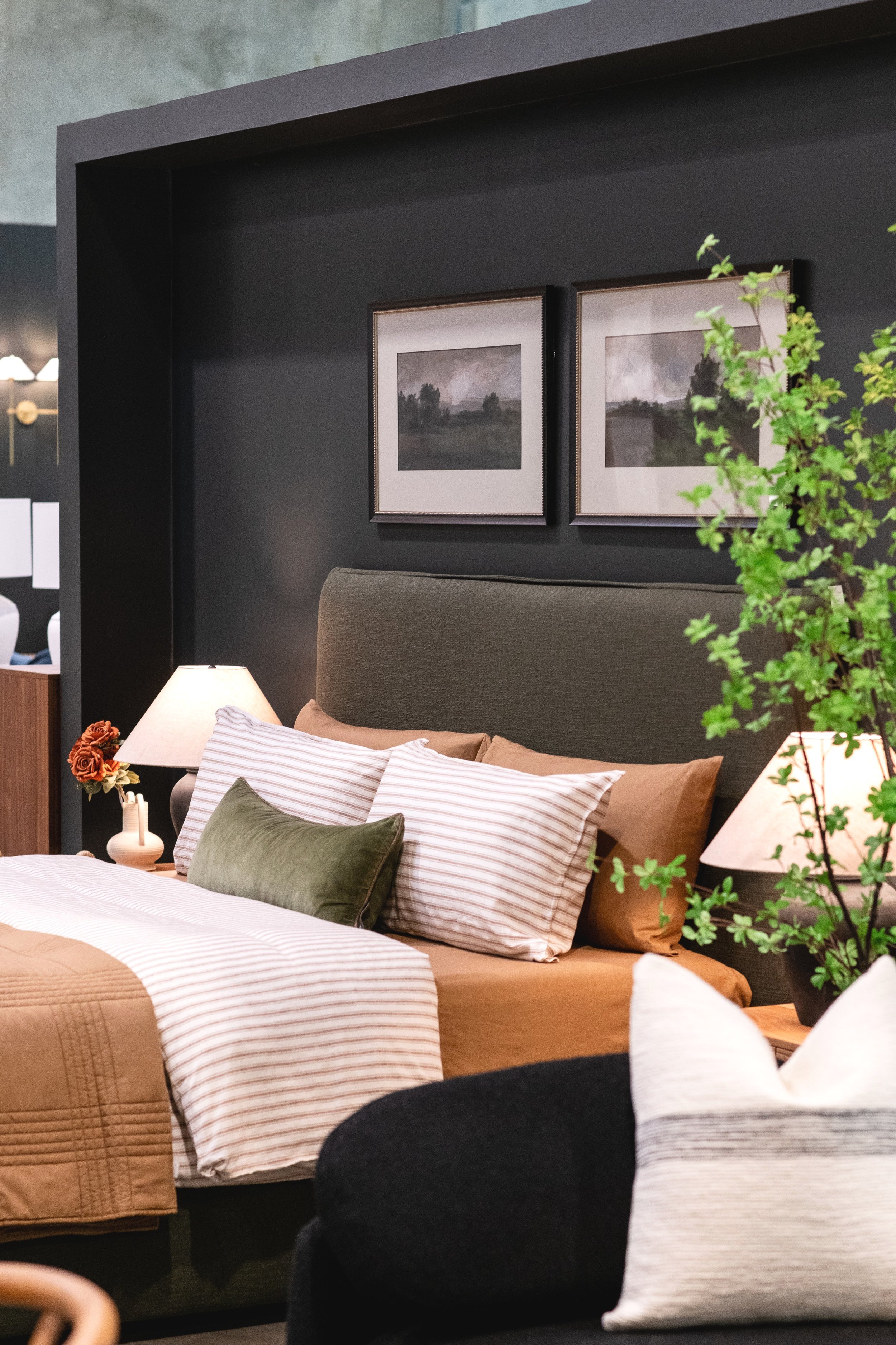 Pezzolo & Co Outlet bedroom display with olive green headboard and neutral bed linens.