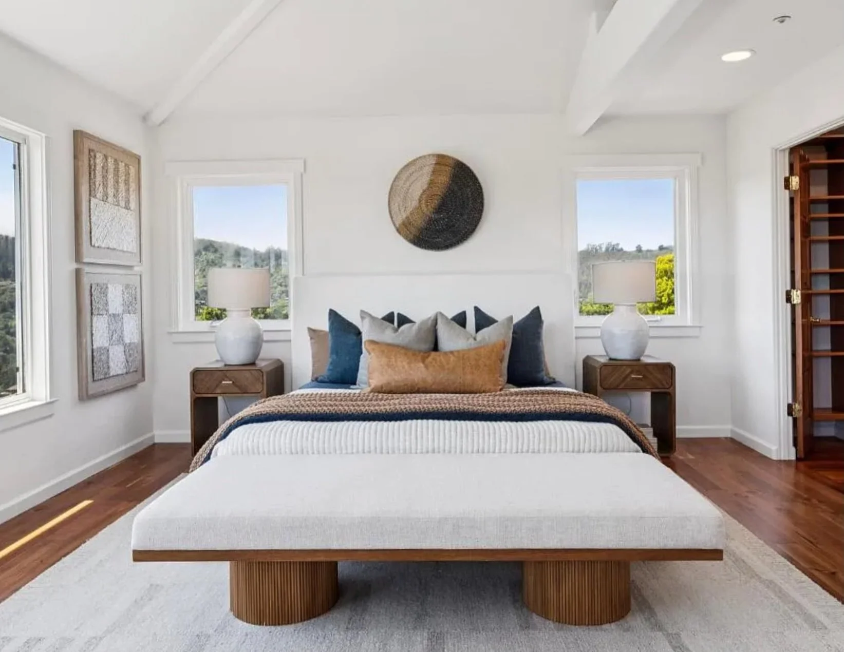 A bedroom should feel like a retreat. This one delivers.

We anchored the space in rich walnut tones, then layered in navy, cognac, and warm neutrals to create a palette that feels grounded and considered. The woven wall disc, textural artwork, and s