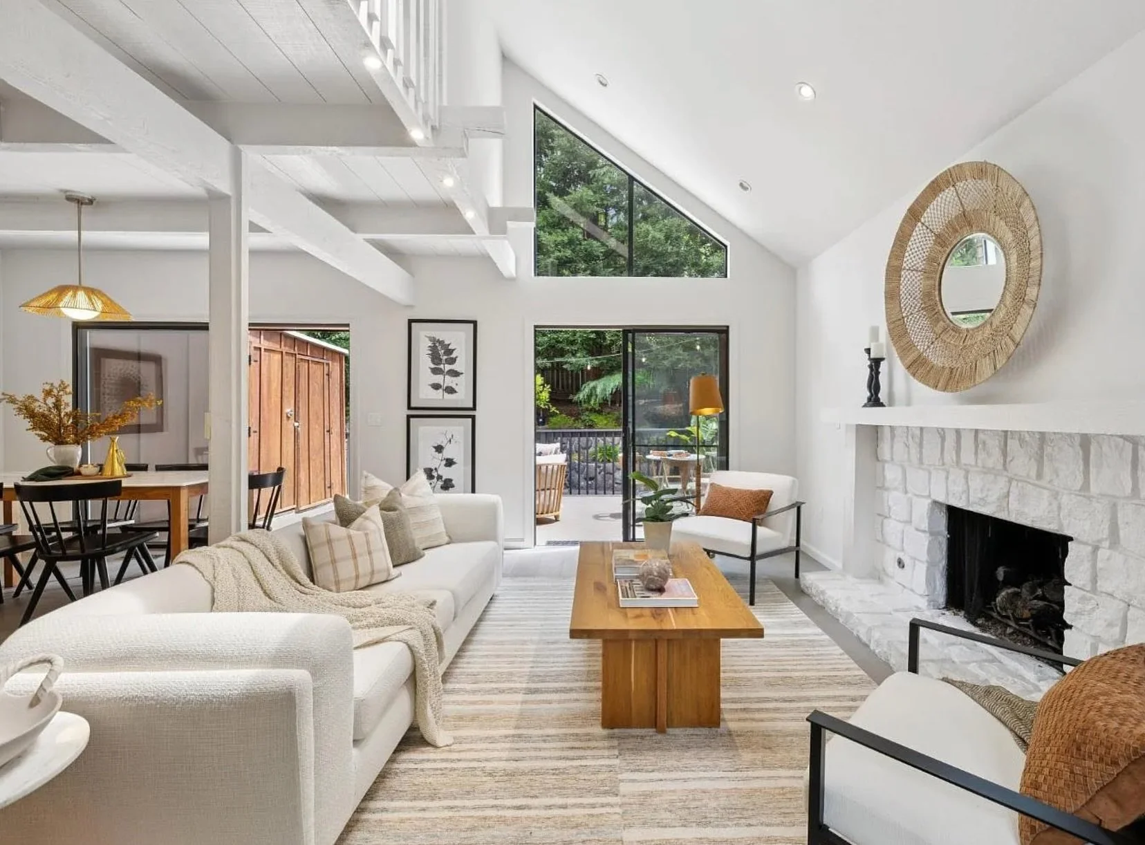 The architecture did us a favor on this one. Soaring beamed ceilings, a dramatic floor-to-ceiling window, an open floor plan that moves effortlessly from living to dining to kitchen &mdash; and a whitewashed stone fireplace that anchors it all withou