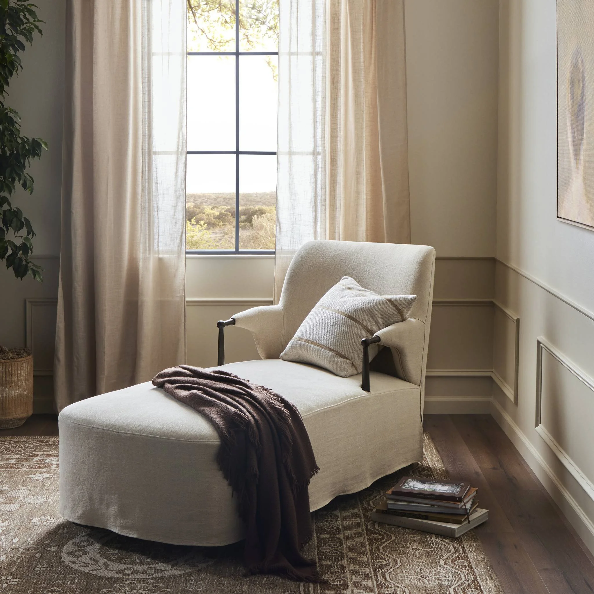 Chaise lounge with decorative pillow near a sunlit window.