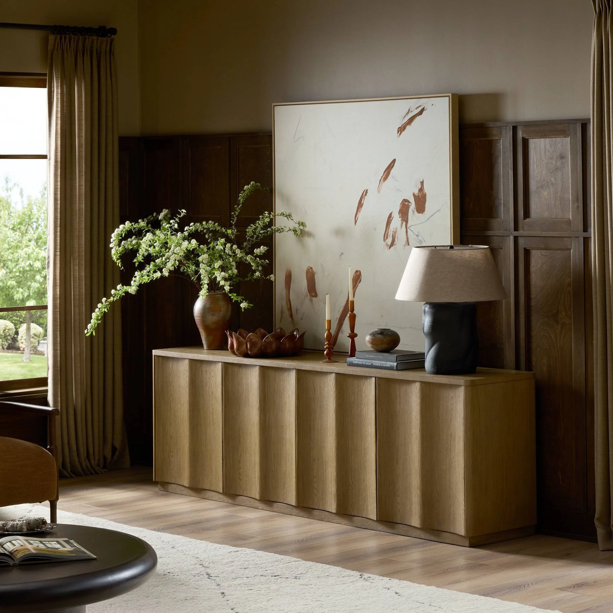 Round wooden table with white boucle fabric chairs on a neutral traditional rug.