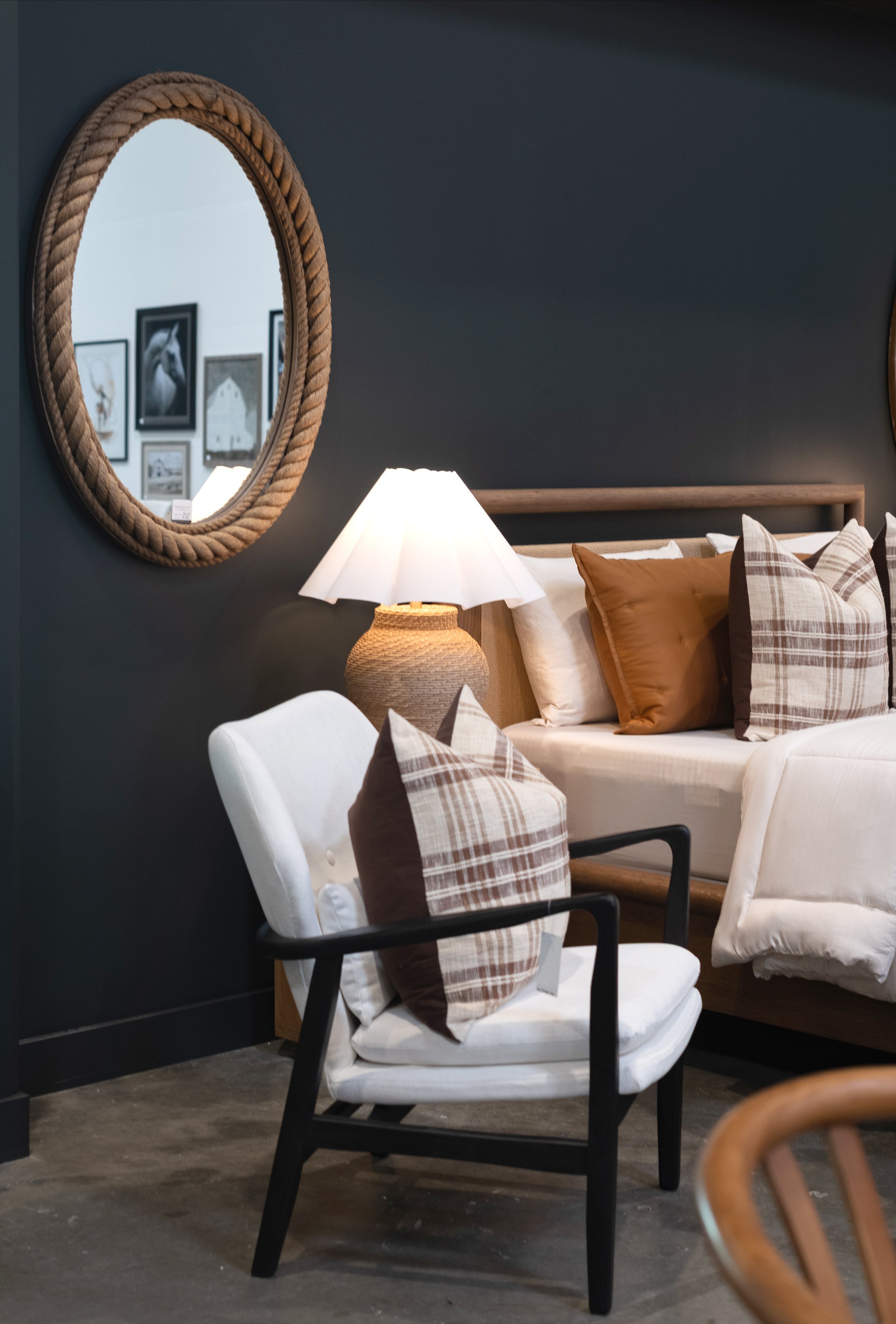 Pezzolo & Co Outlet light colored chair and modern bed with decorative plaid pillows.