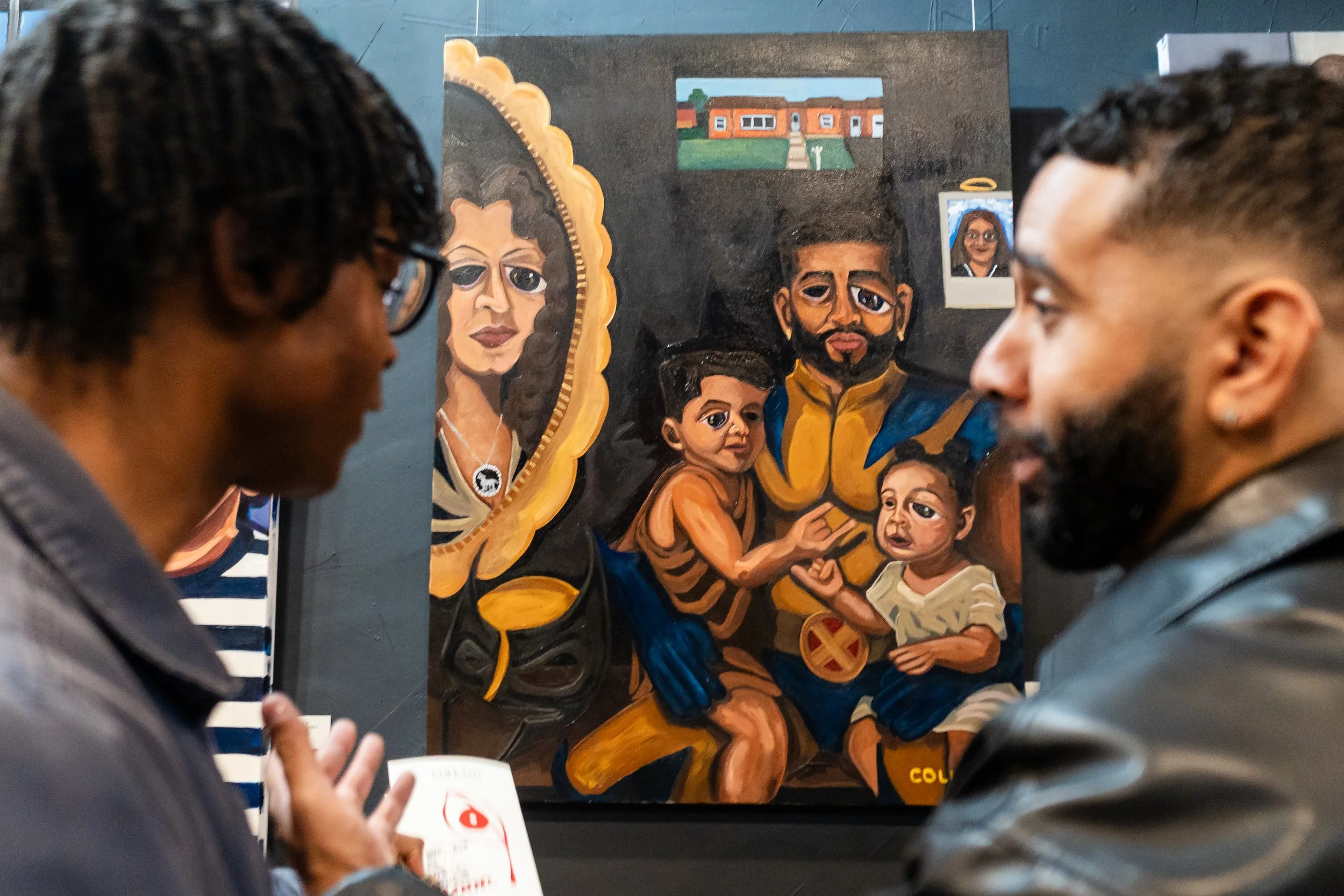 Two people observing a colorful, abstract painting of a family, including two children and two adults, with a portrait of a woman in a decorative frame on the wall.
