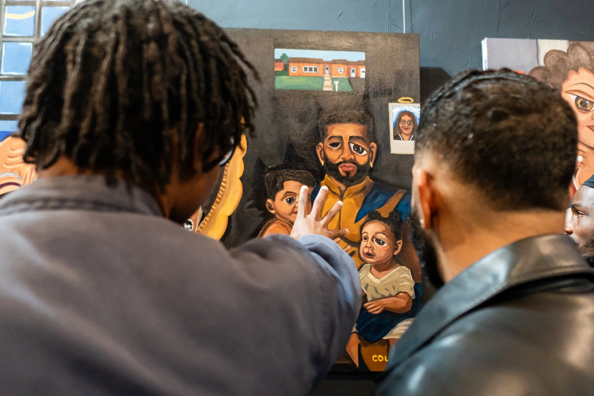 Two individuals viewing a colorful painting of a father with three children, with a house and landscape in the background.