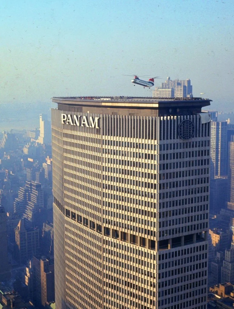 Helicopter flying near the top of the Pan Am skyscraper in a city skyline