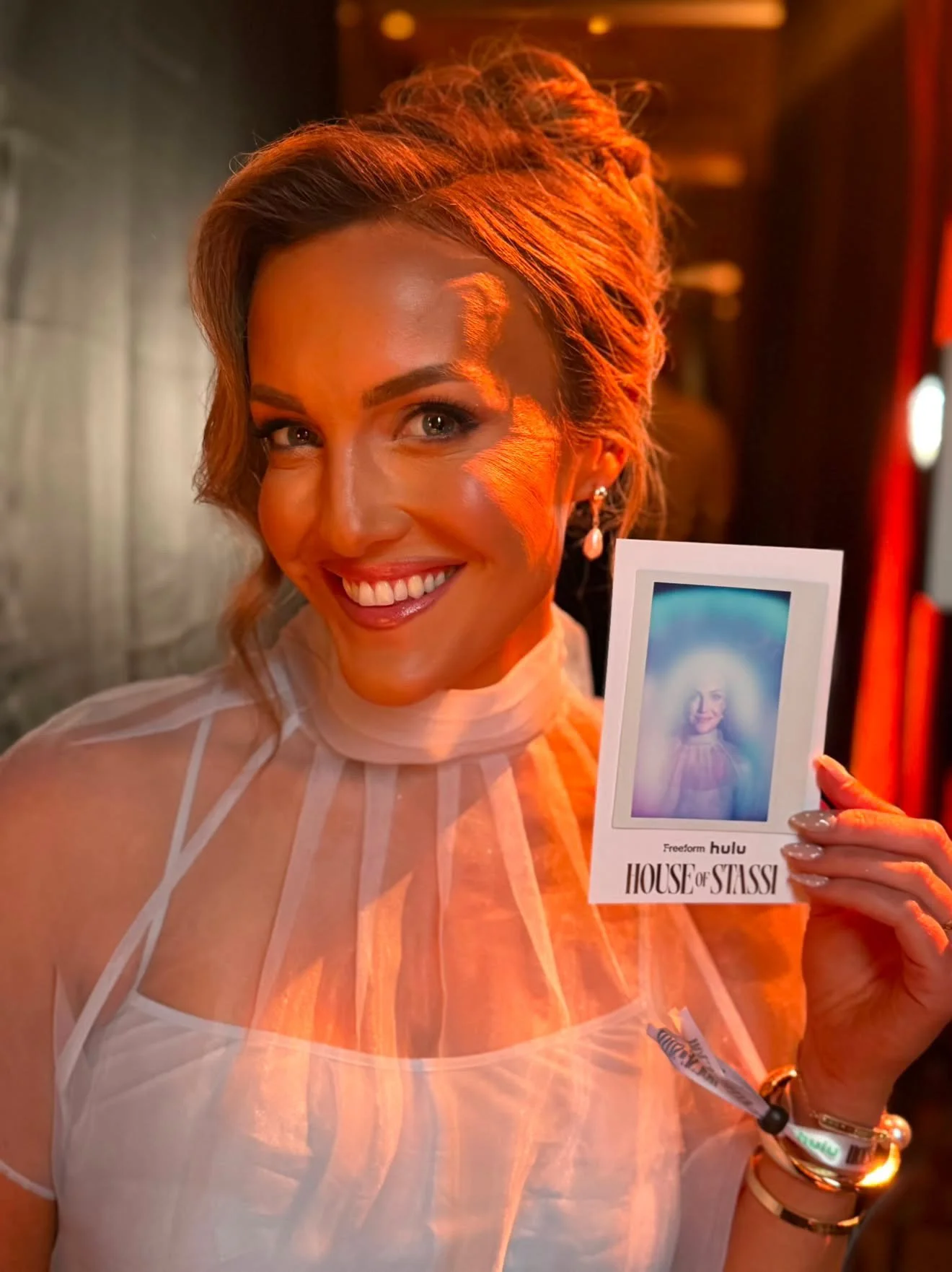Caitlin Marshall holding her aura portrait at the House of Stassi launch event