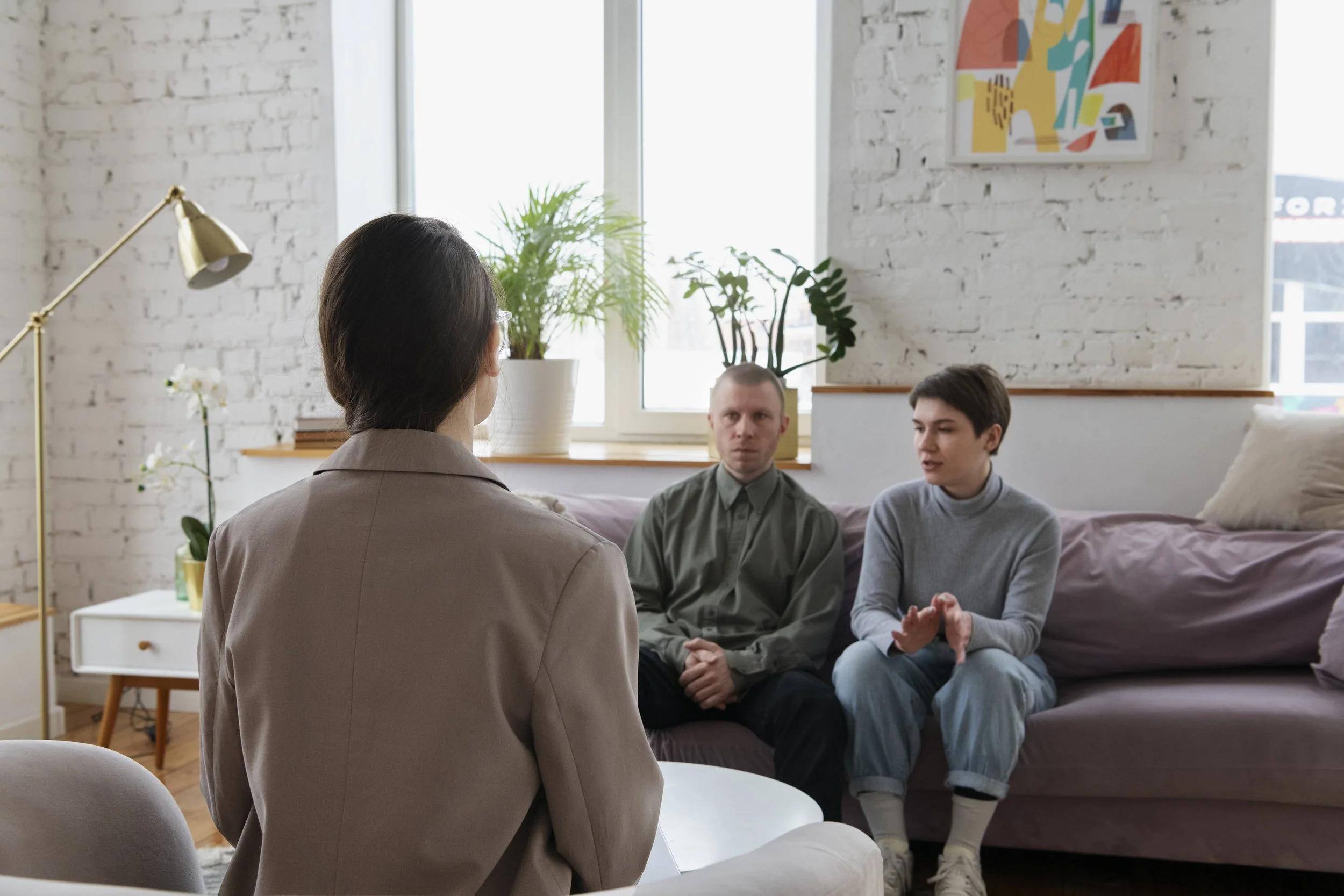 A couple participating in a cognitive behavioral therapy session with a therapist in a modern Denver office.