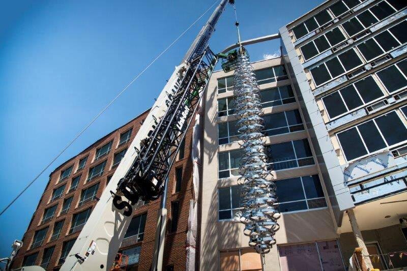 A crane lifts the stainless steel sculpture above the hotel entry