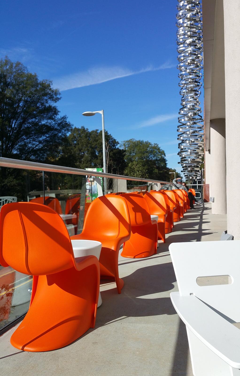 Exterior seating area with orange chairs and a view of the steel sculpture