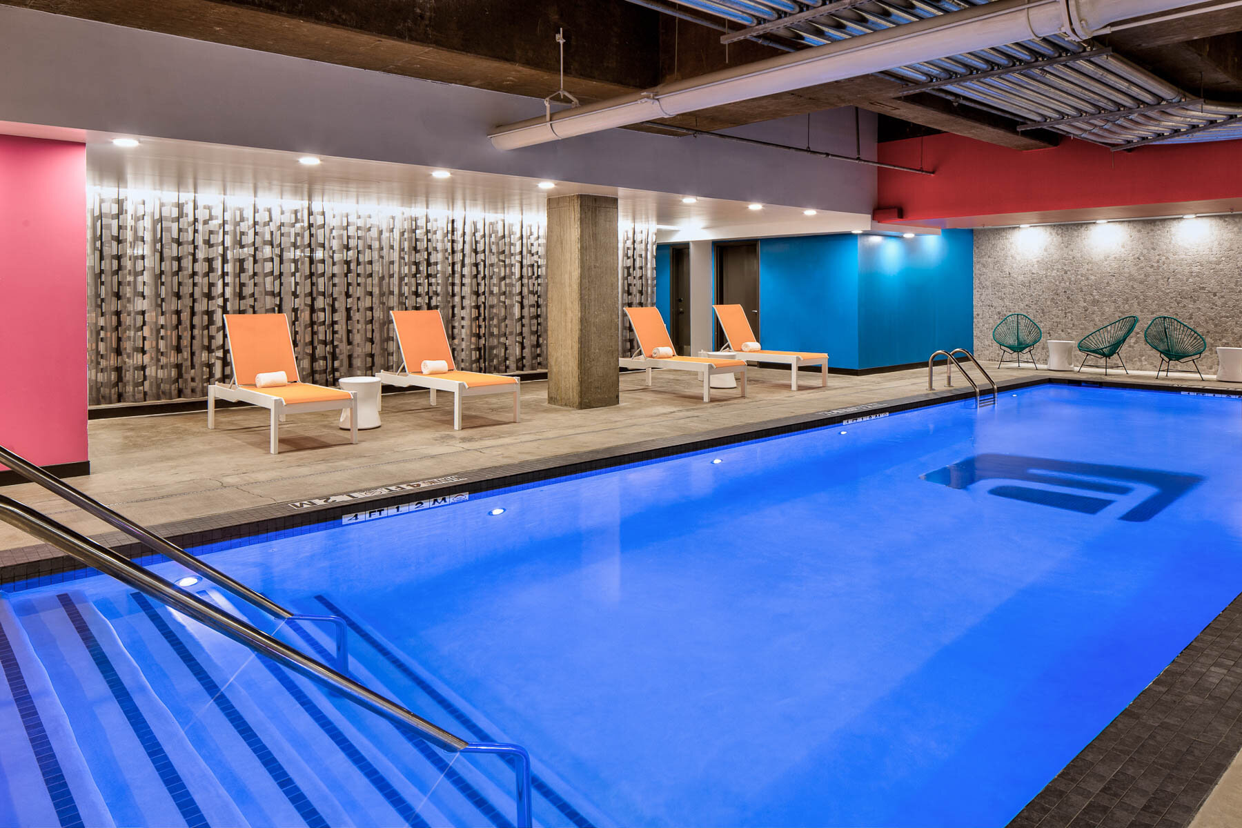 Indoor pool lined with orange lounge chairs