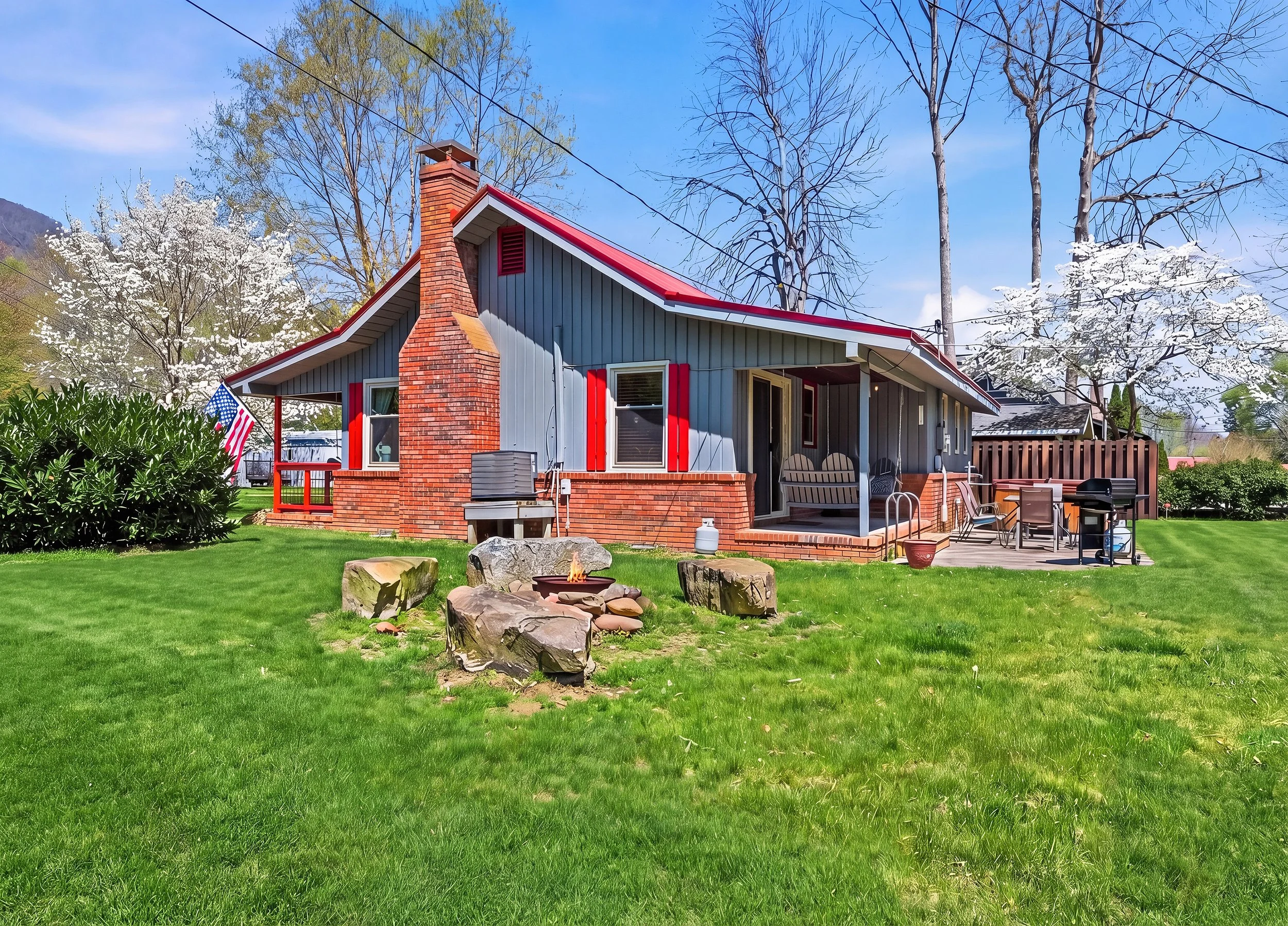 A beautiful yard on the creek with a patio, hot tub, grill and porch sitting.