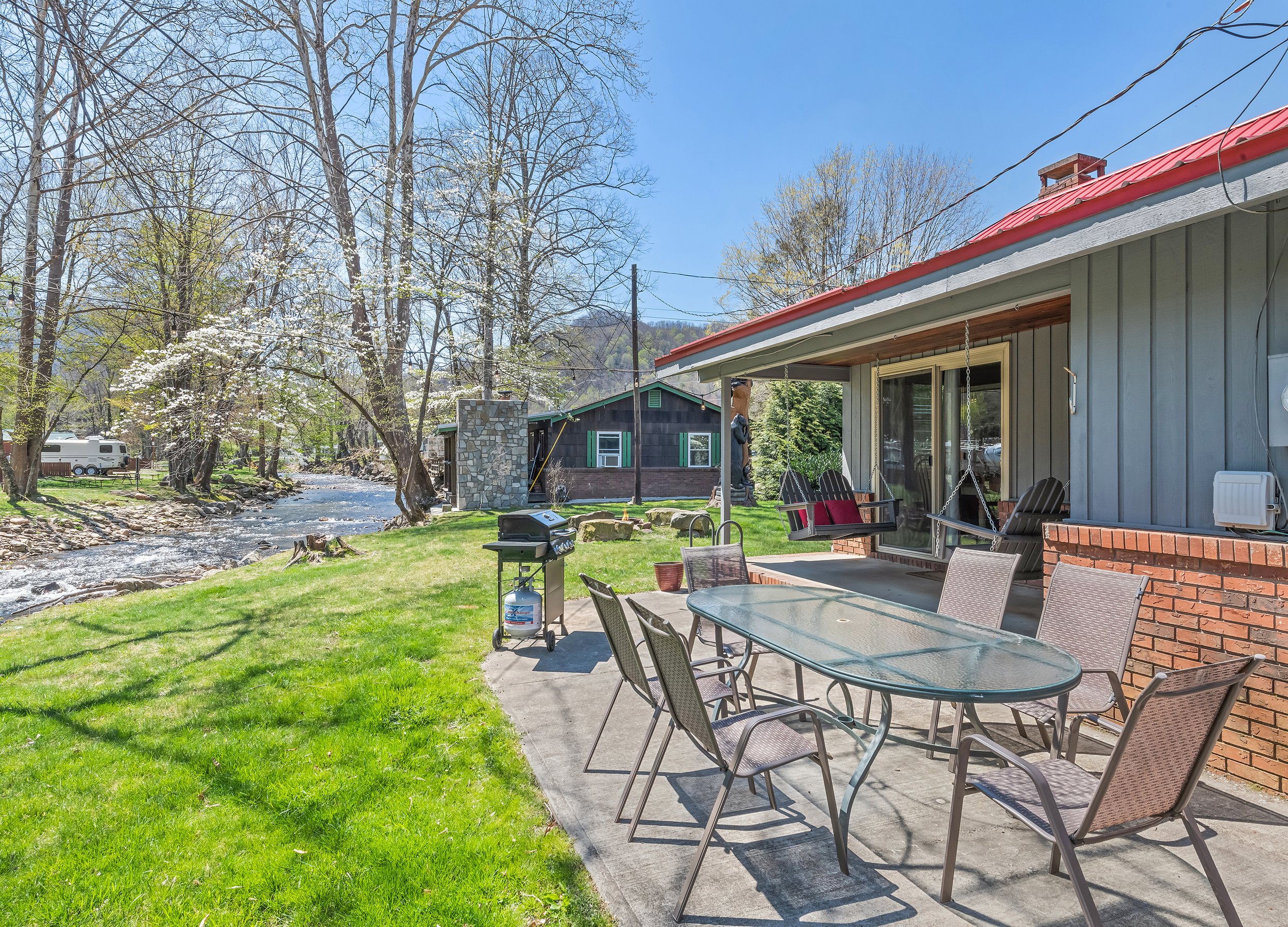Patio area with grill, hot tub, table with seating for 6.  Covered porch with 2 porch swings.