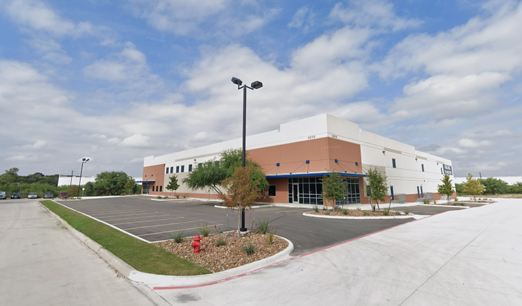 Empty parking lot in front of a modern retail or commercial building with trees and landscaping