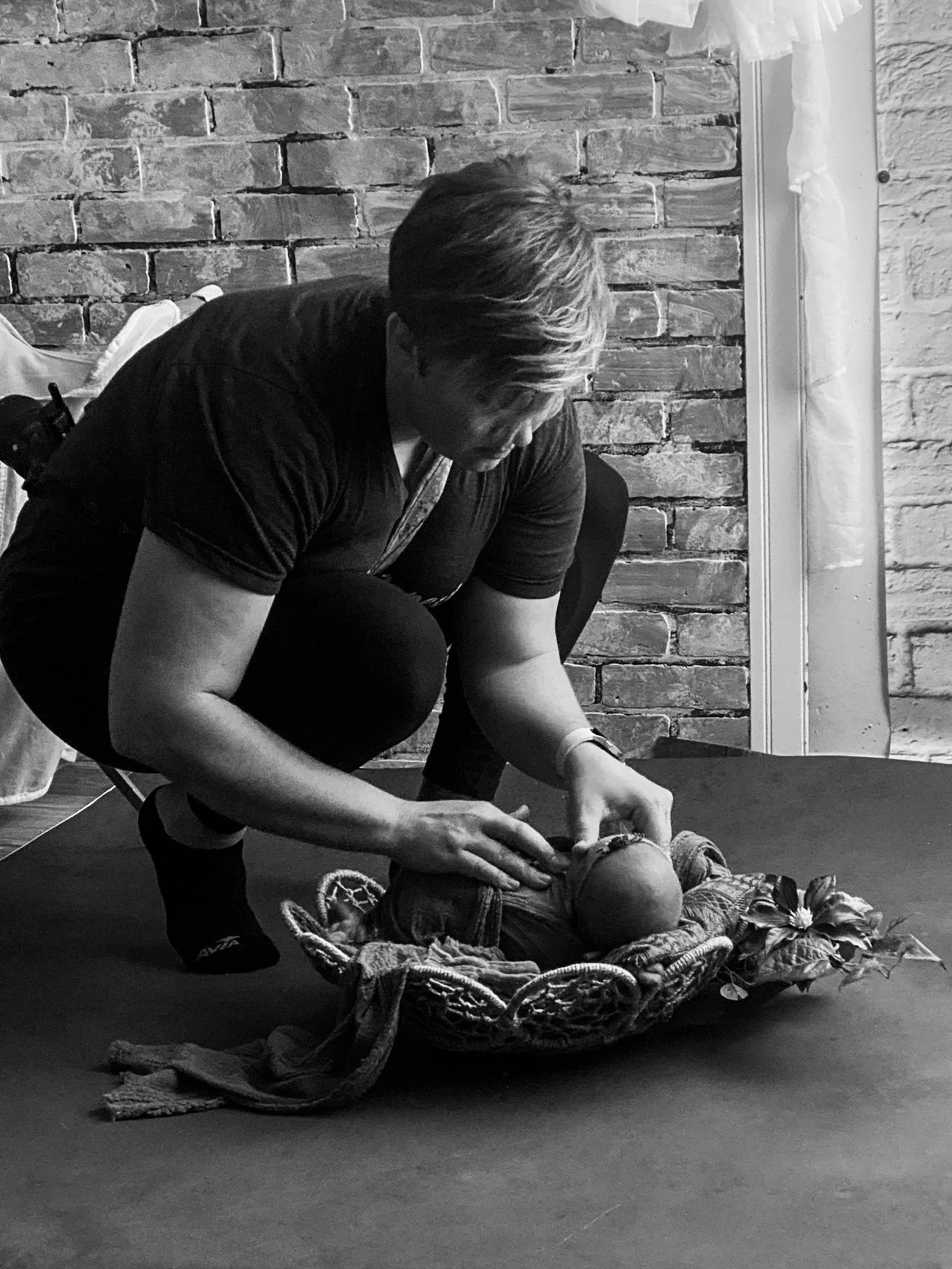 Newborn photographer Emily gently positioning a baby during a behind-the-scenes studio photography session in Syracuse, Utah.